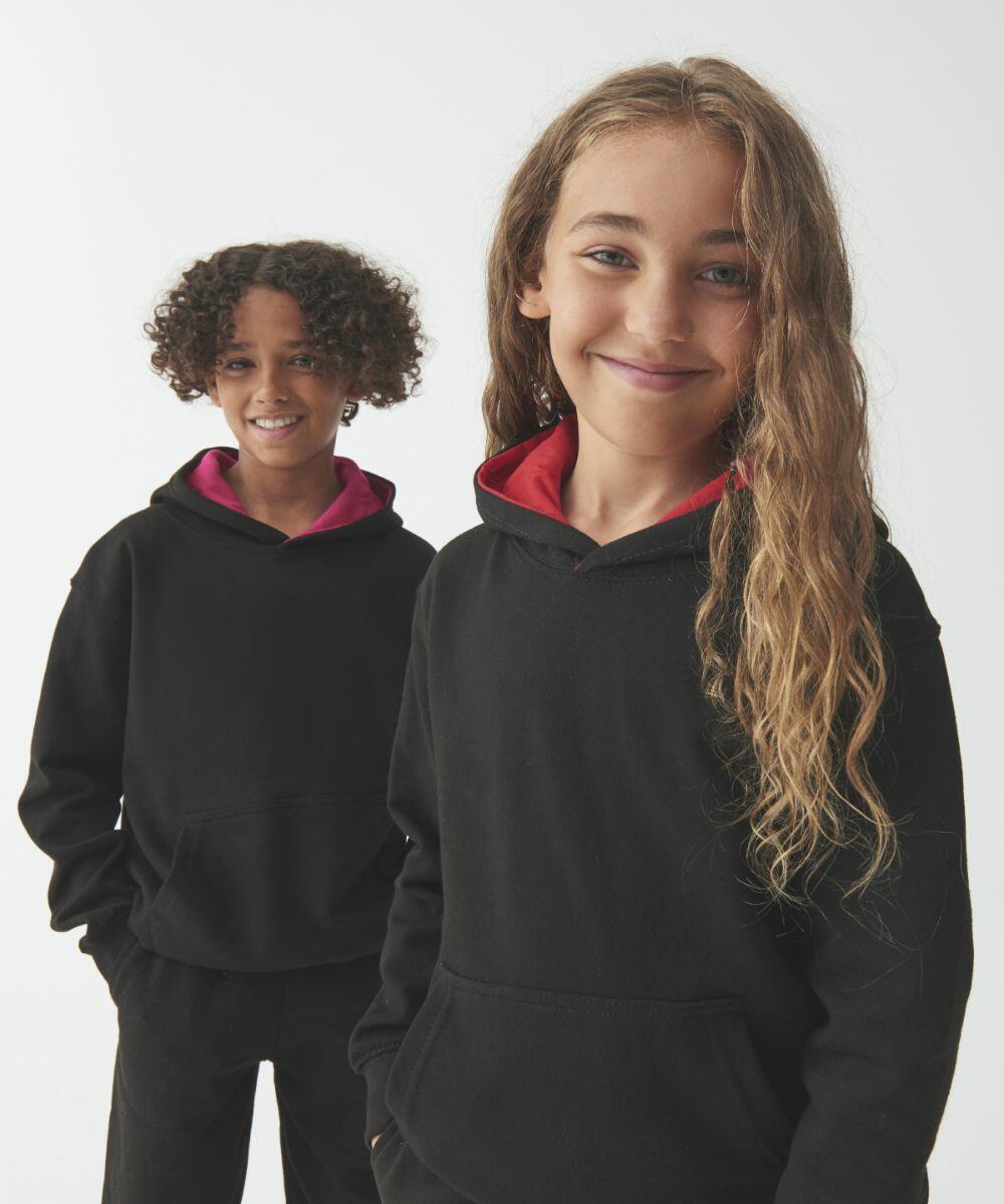 Two children wearing black AWDis Just Hoods JH03J hoodies with red linings stand smiling in front of a plain white background.