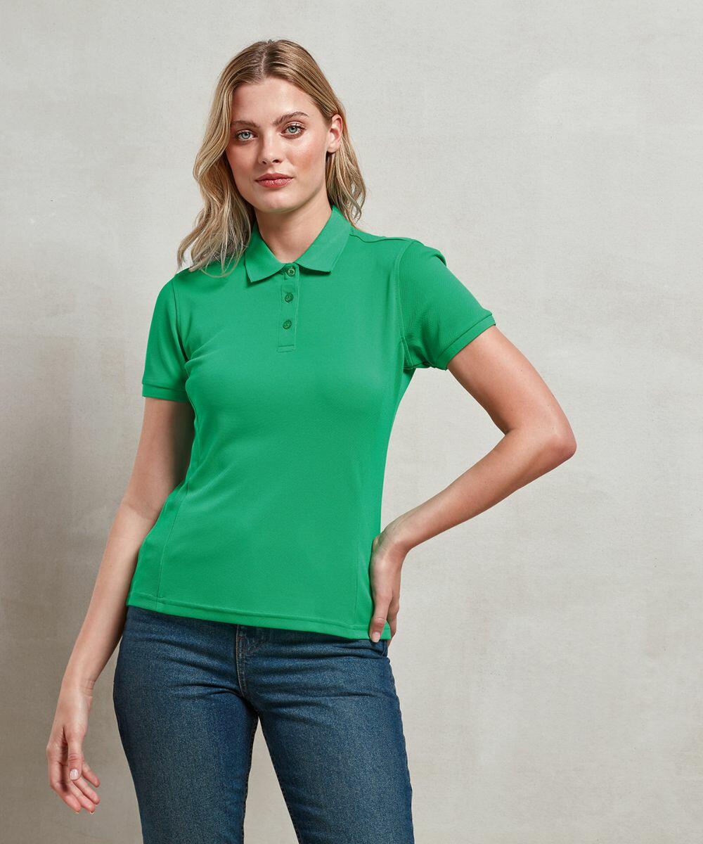 A woman in a green polo shirt and blue jeans stands against a plain background, with one hand on her hip and the other relaxed at her side, showcasing the Premier PR632.