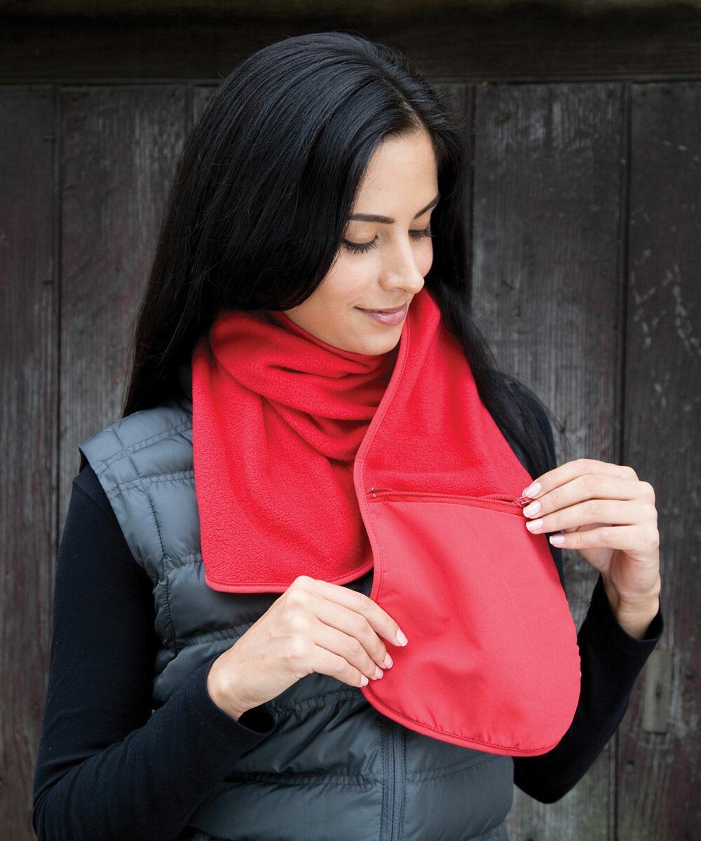 A person with long dark hair wearing a red scarf and a grey padded vest is looking down and unzipping a small pocket on the Result R100A.