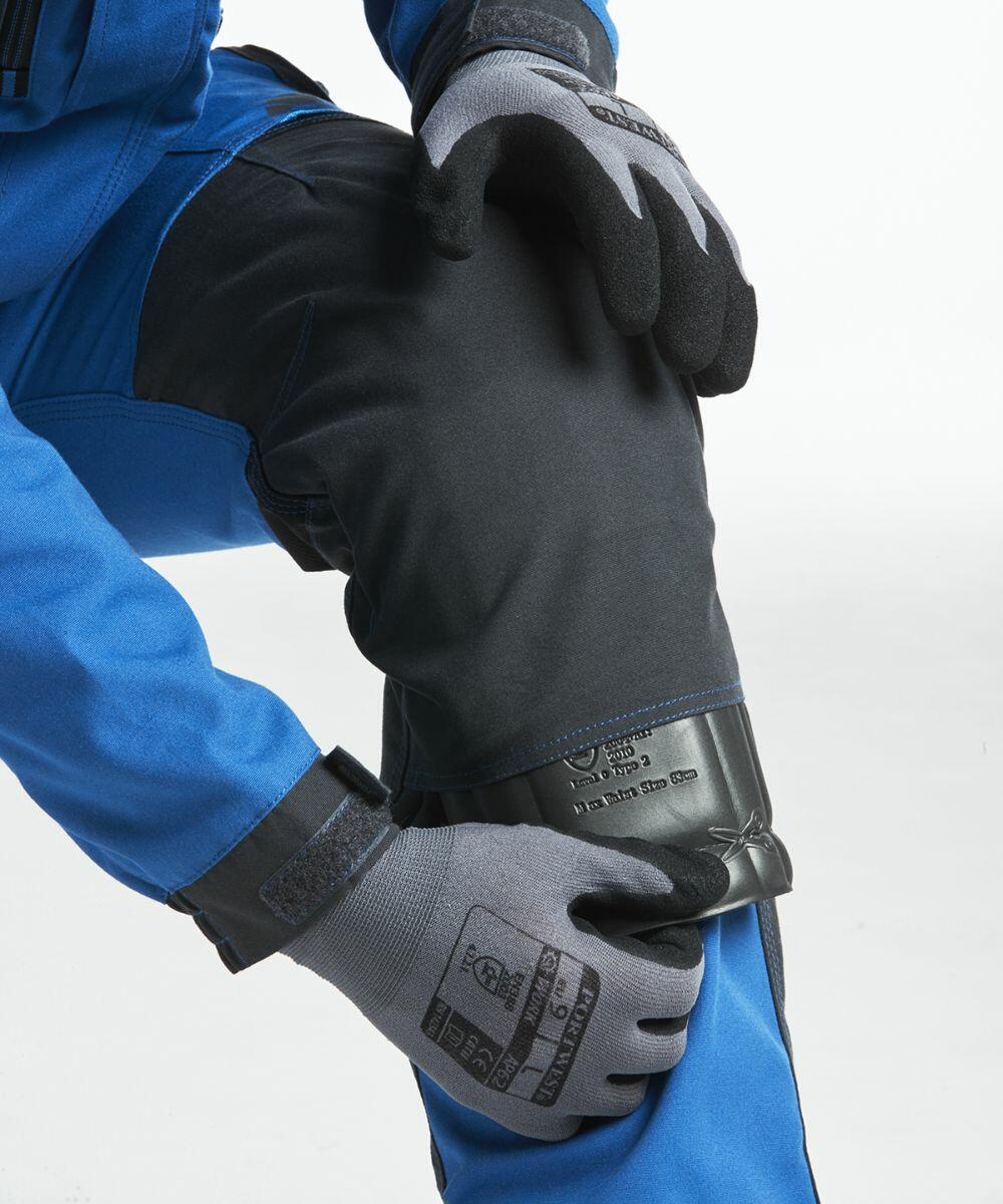 A person wearing a blue and black outfit with gray gloves is shown adjusting a Portwest PW102 around their knee.