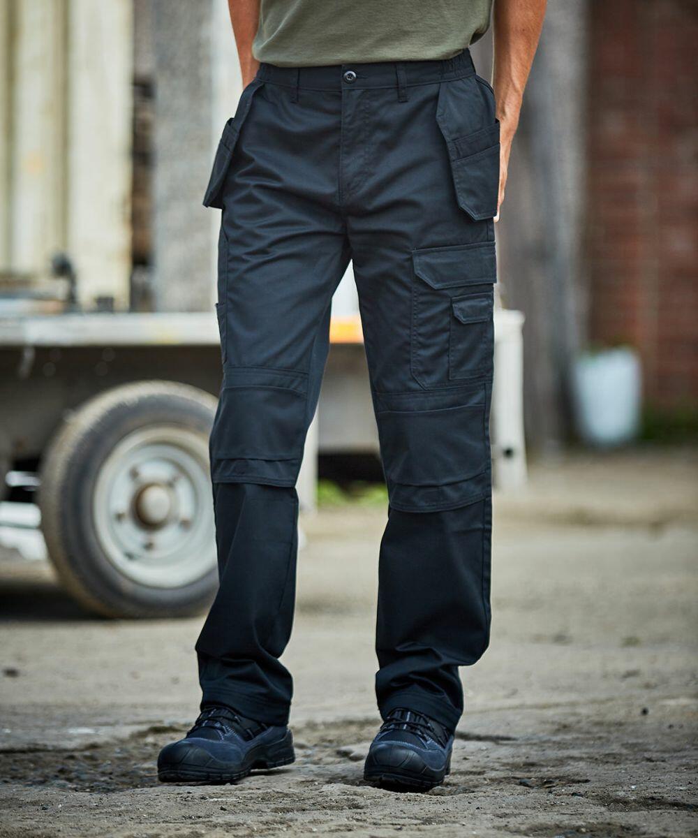 Person wearing ProRTX RX603 cargo pants and black boots standing on a concrete surface. A trailer and building are visible in the background.