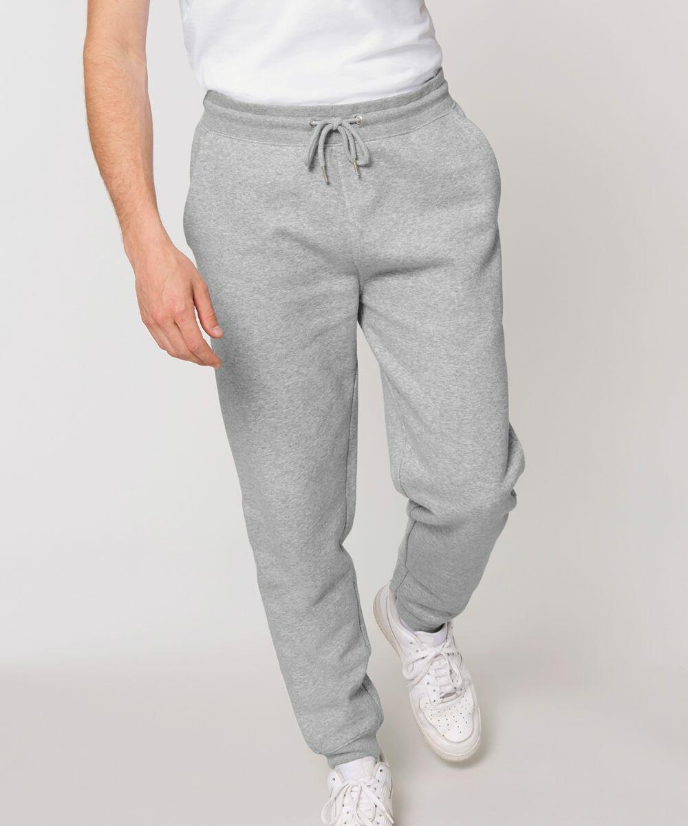 A person wearing gray sweatpants, a white shirt, and white Stanley/Stella SX073 sneakers stands against a plain background.