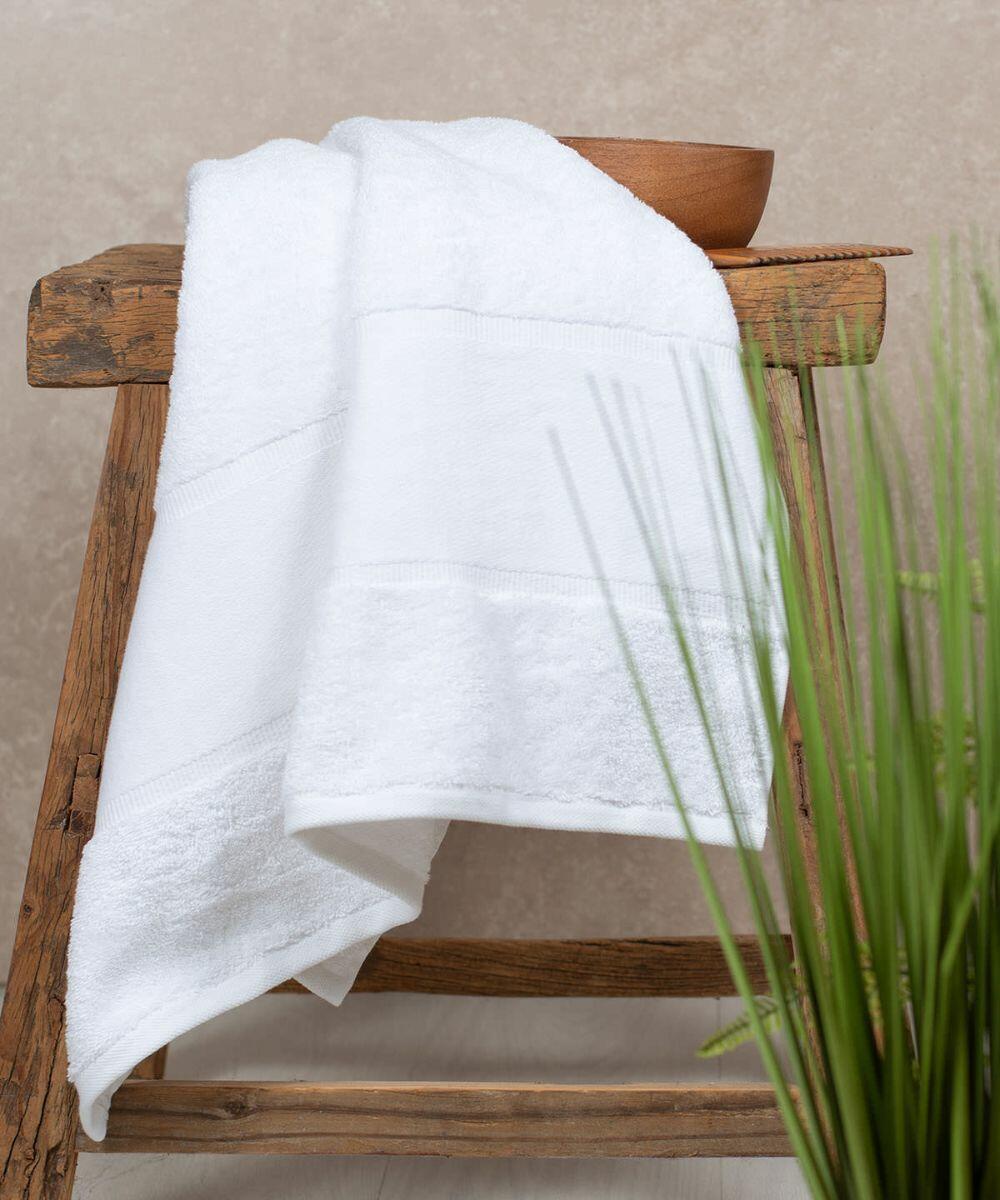 A Towel City TC505 hangs over a rustic wooden stool beside a small wooden bowl and green plant.