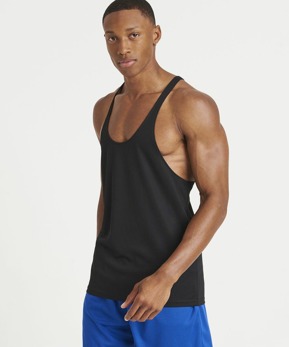 A man wearing an AWDis Just Cool JC009 black tank top and blue shorts stands against a plain white background.