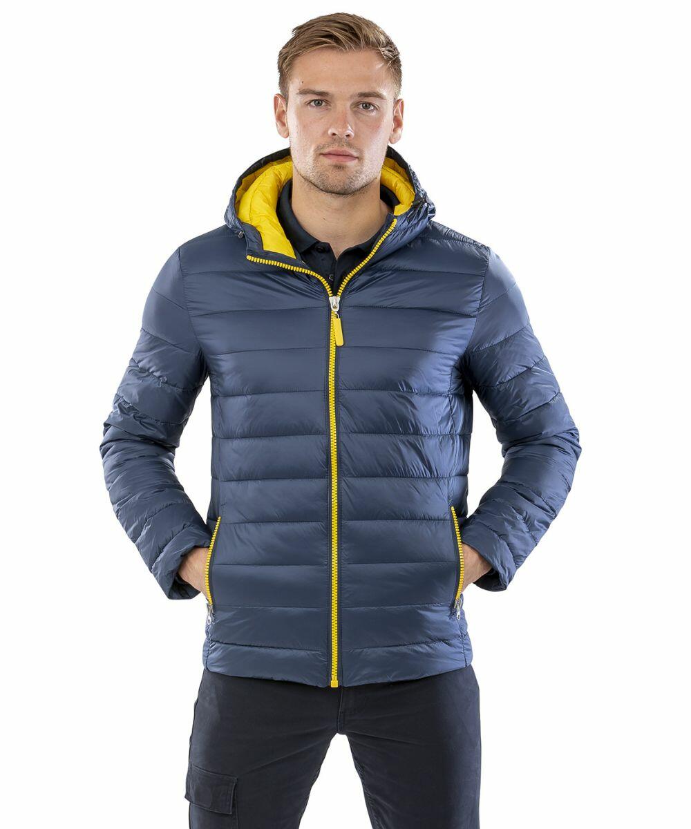 A man wearing a blue Result R194M jacket with a yellow zipper and hood lining, standing with hands in pockets.