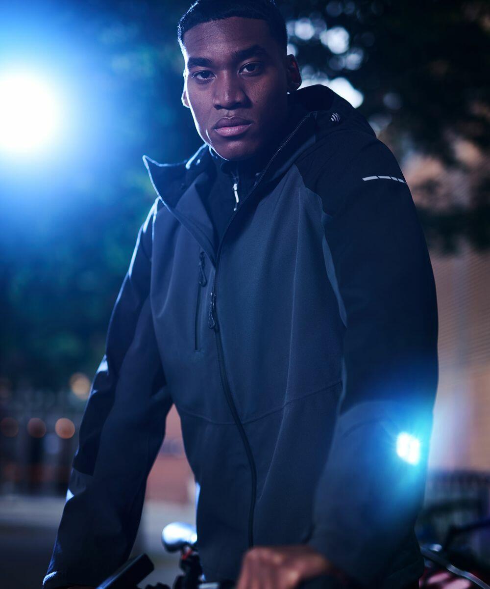 A person wearing a Regatta RG585 jacket is standing outdoors at night with blue lights in the background.