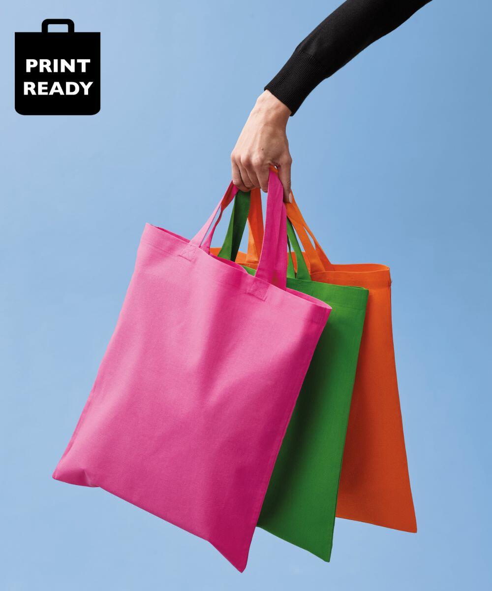 A hand holds three reusable Nutshell RL110 tote bags in pink, green, and orange against a blue background. The top left corner features a "PRINT READY" icon.