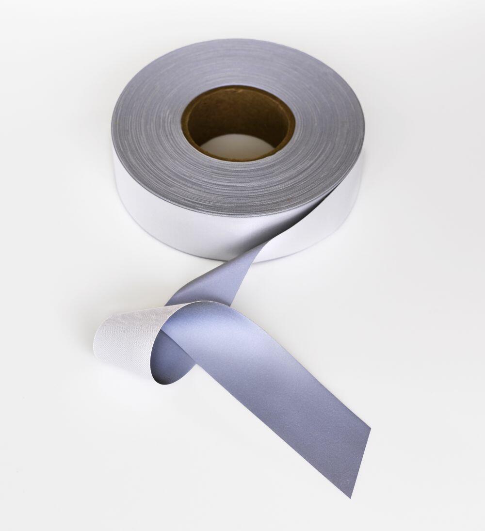 A roll of Yoko's YK203 gray ribbon partially unspooled on a white background.