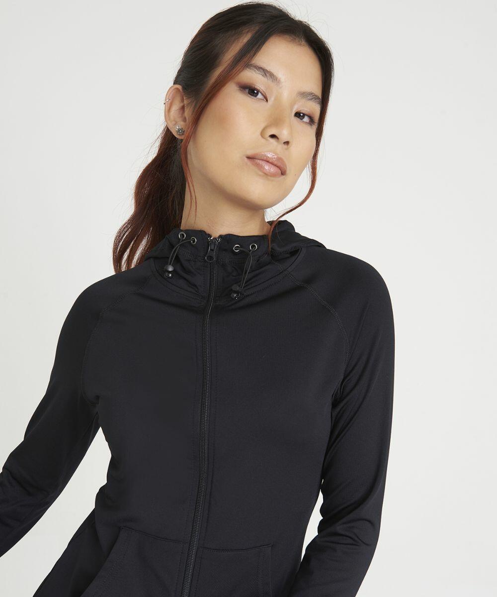 Person wearing a black JC058 zipped jacket with a hood by AWDis Just Cool, looking at the camera against a plain white background.