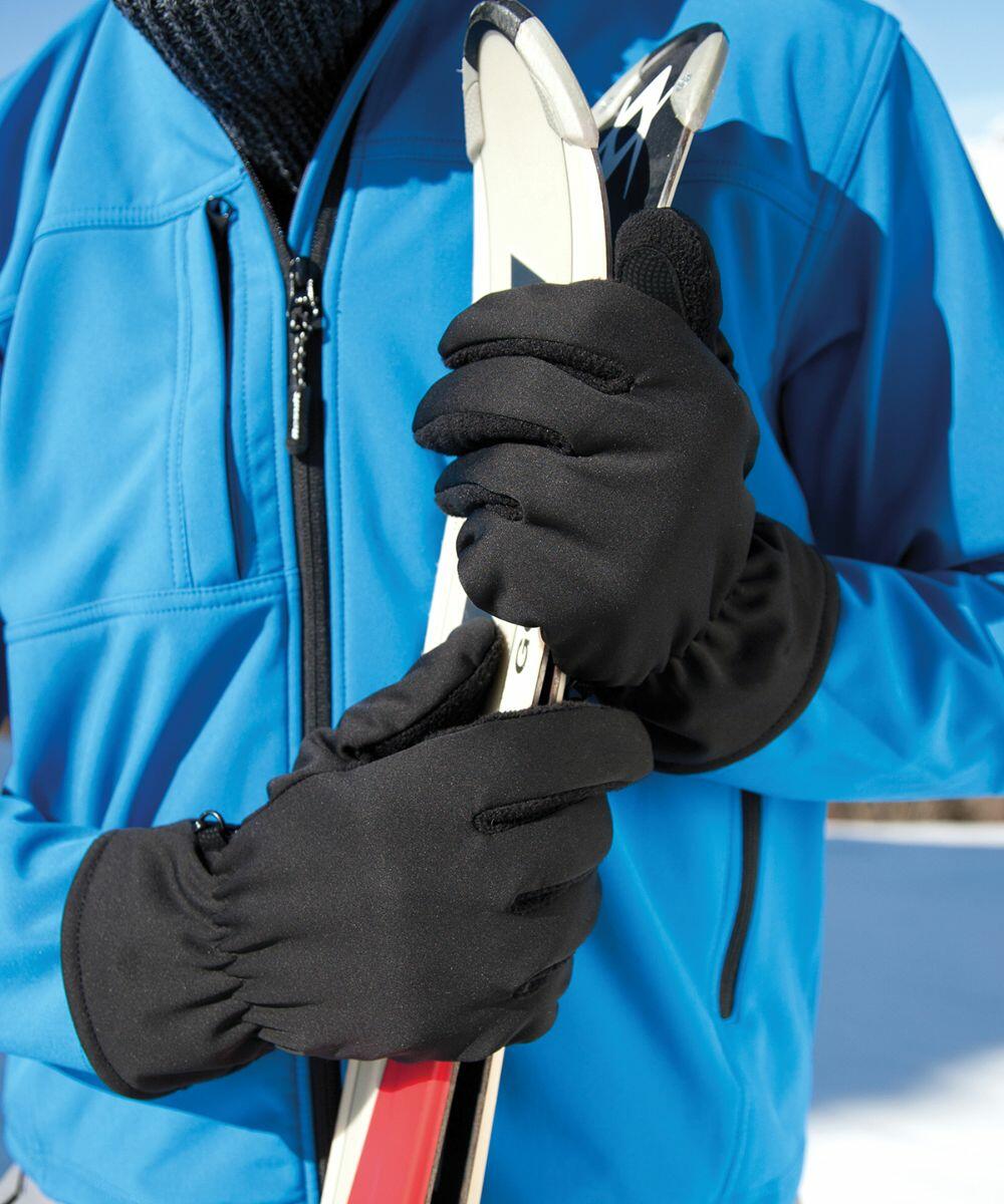 A person in a blue jacket and black gloves holds a pair of Result R364X ski poles against a snowy background.