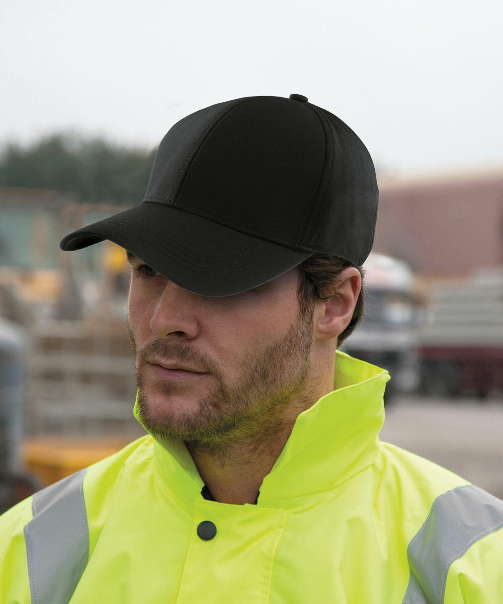 Person wearing a black Result RC73X baseball cap and yellow high-visibility jacket stands outdoors with a neutral expression.