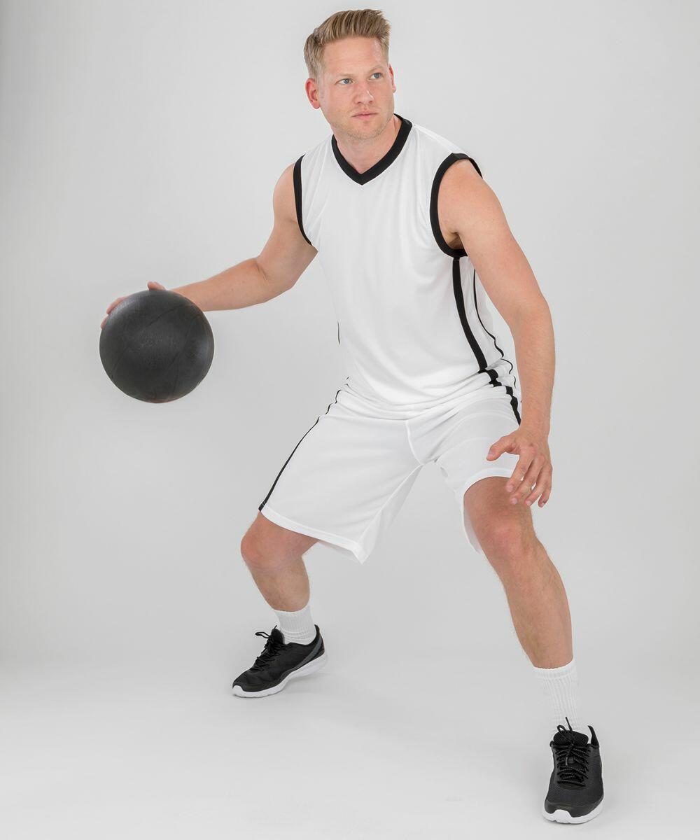 A person in a white basketball uniform and black Spiro S278M sneakers is holding a basketball in a crouched, ready-to-play position against a plain background.