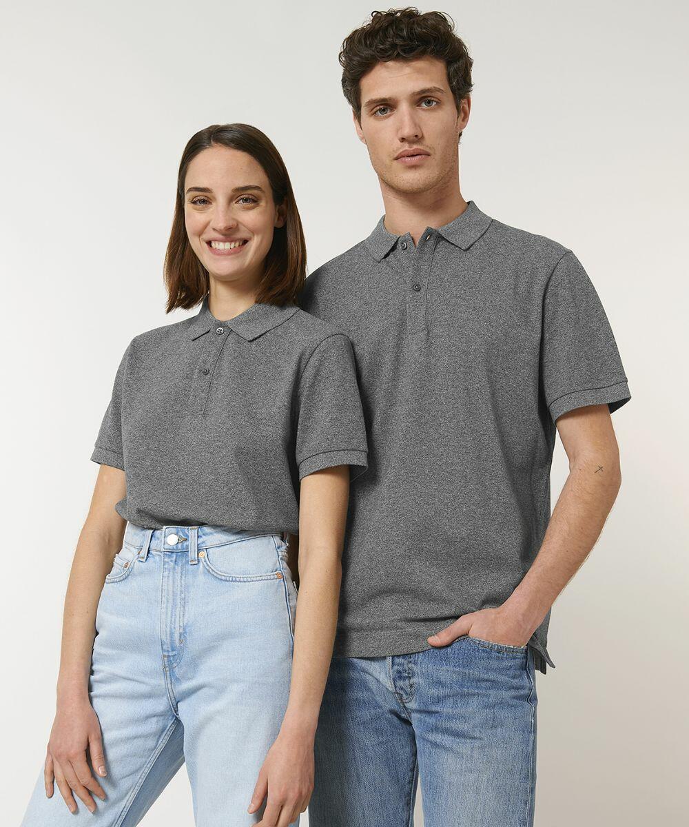 Two people stand side by side wearing Stanley/Stella SX126 grey polo shirts and blue jeans. The person on the left has short hair and smiles, while the person on the right has curly hair and a neutral expression.