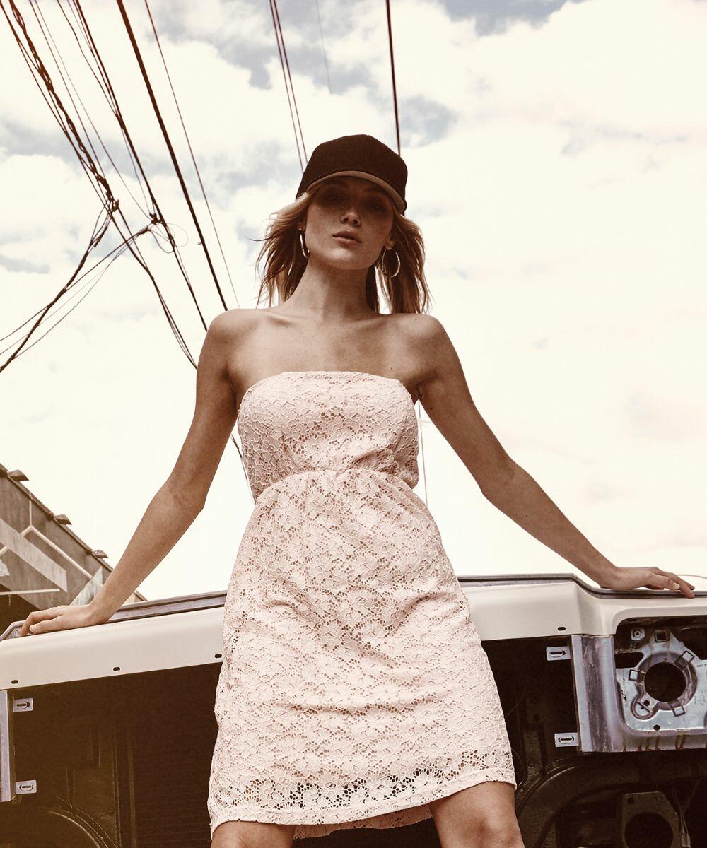 Woman in a strapless lace dress and a YP058 by Flexfit By Yupoong stands in front of an industrial backdrop with power lines overhead.