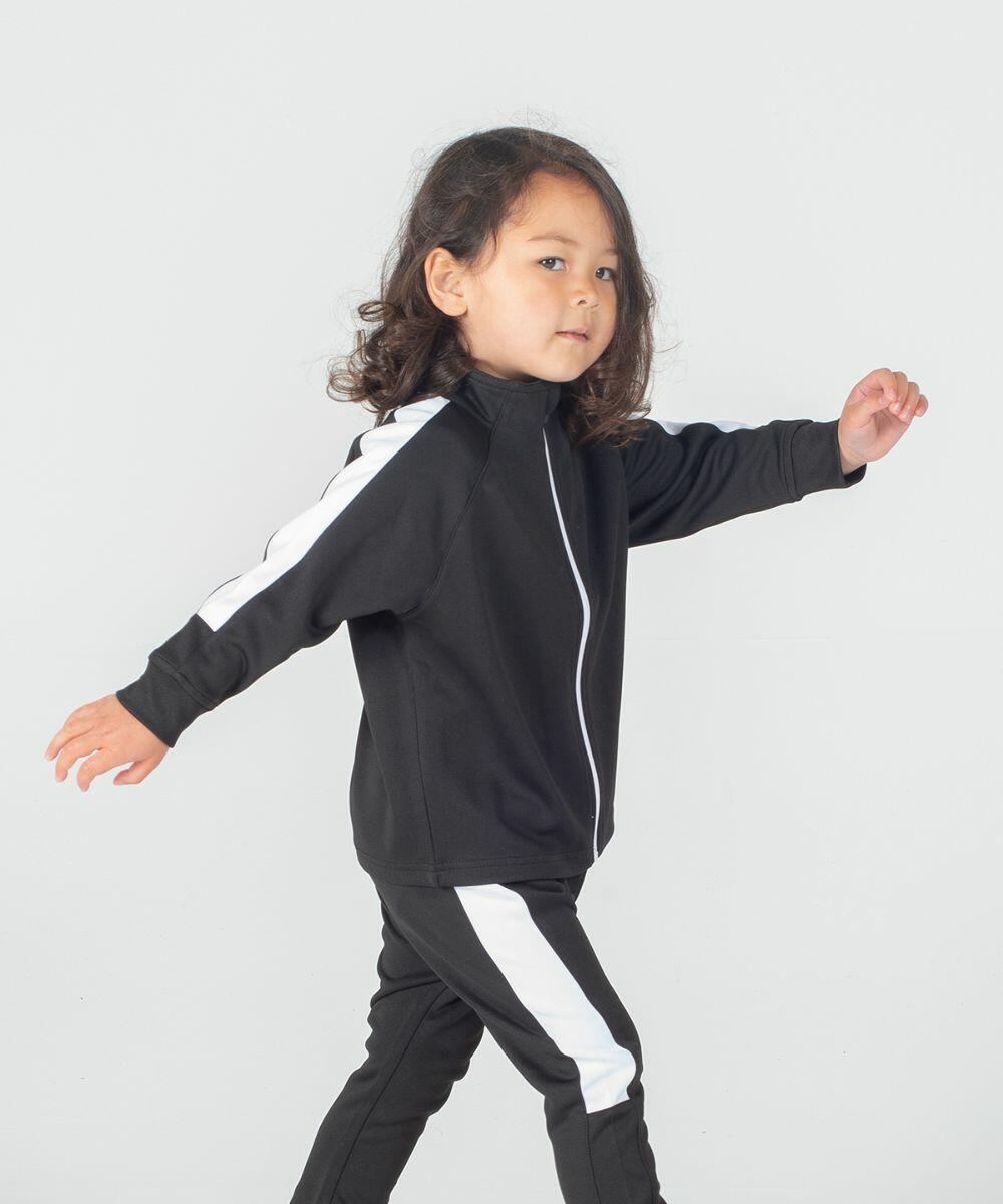 A young child with shoulder-length hair walks confidently, wearing a black Larkwood LW820 tracksuit with white vertical stripes on the arms and legs. The child gazes slightly to the side.