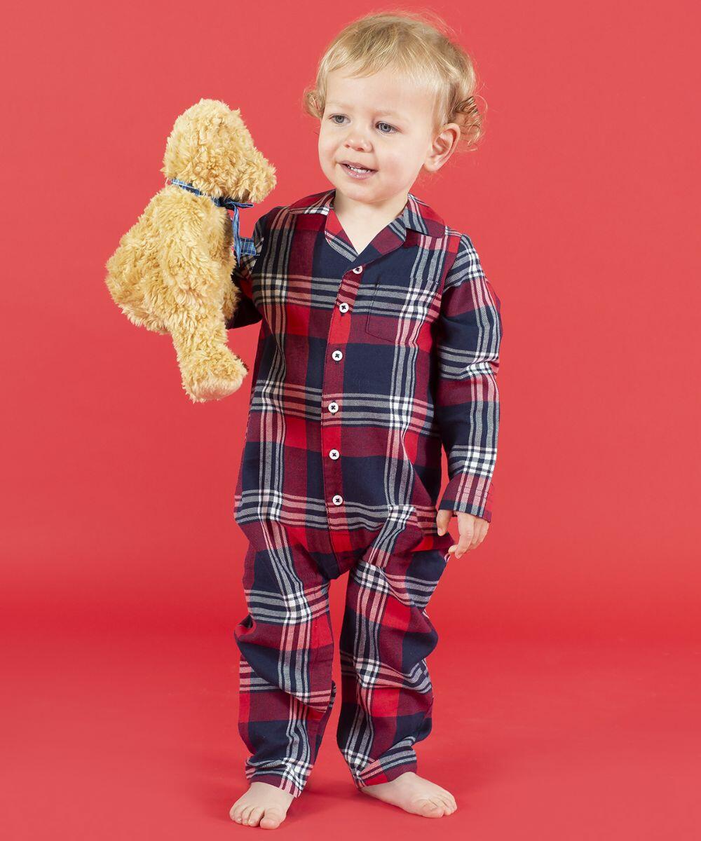 A young child wearing red and blue plaid pajamas holds a Mumbles MM001 against a red background.