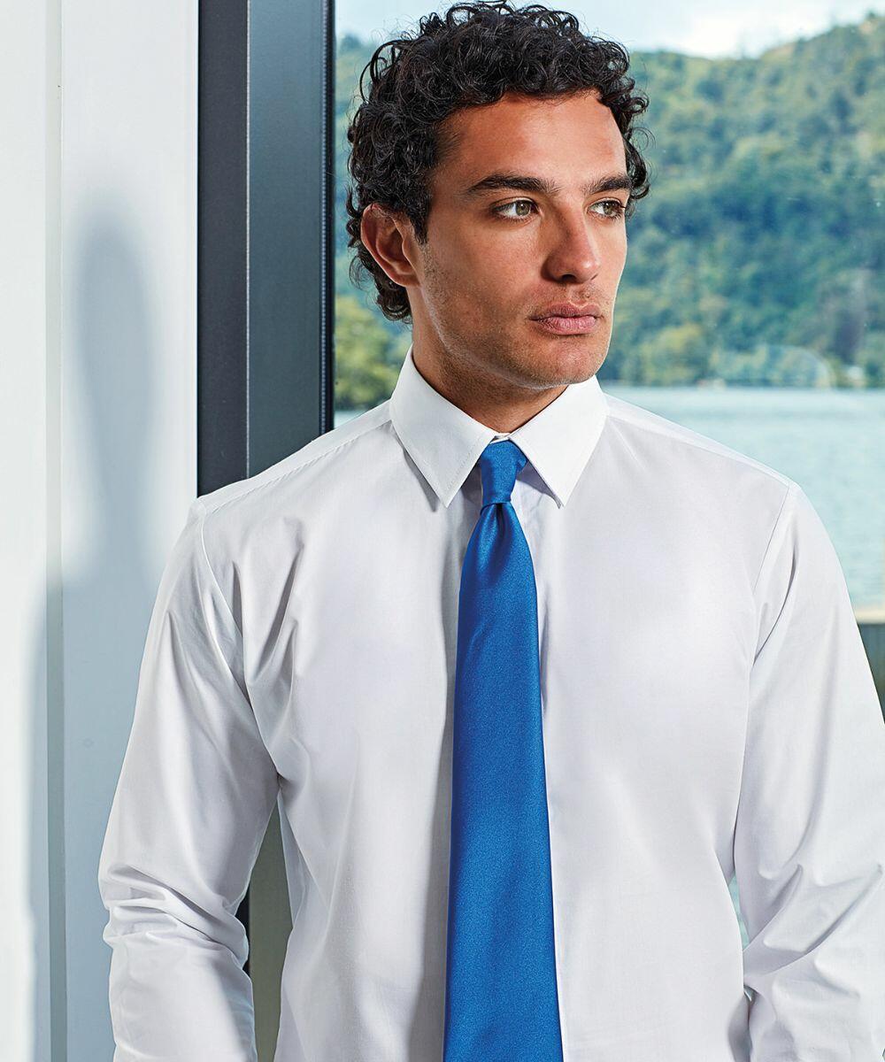 A man with curly hair wearing a white dress shirt and blue tie looks to the side. There is a large window behind him showing a natural landscape with trees and water. He is using the PR750 by Premier.