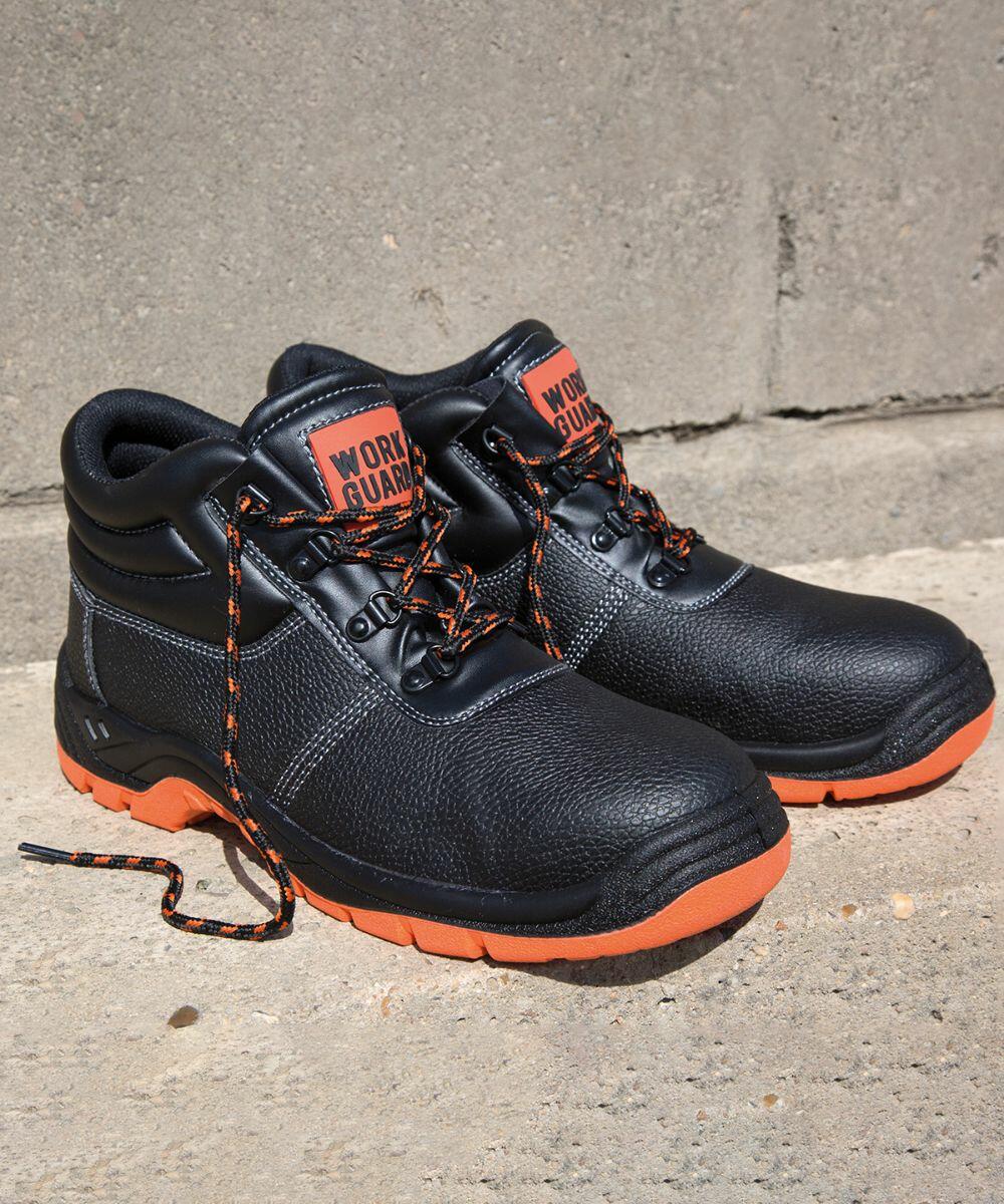 A pair of black and orange R340X work boots by Result with "WORLD GUARD" label, positioned on a concrete surface. One boot has its laces untied.