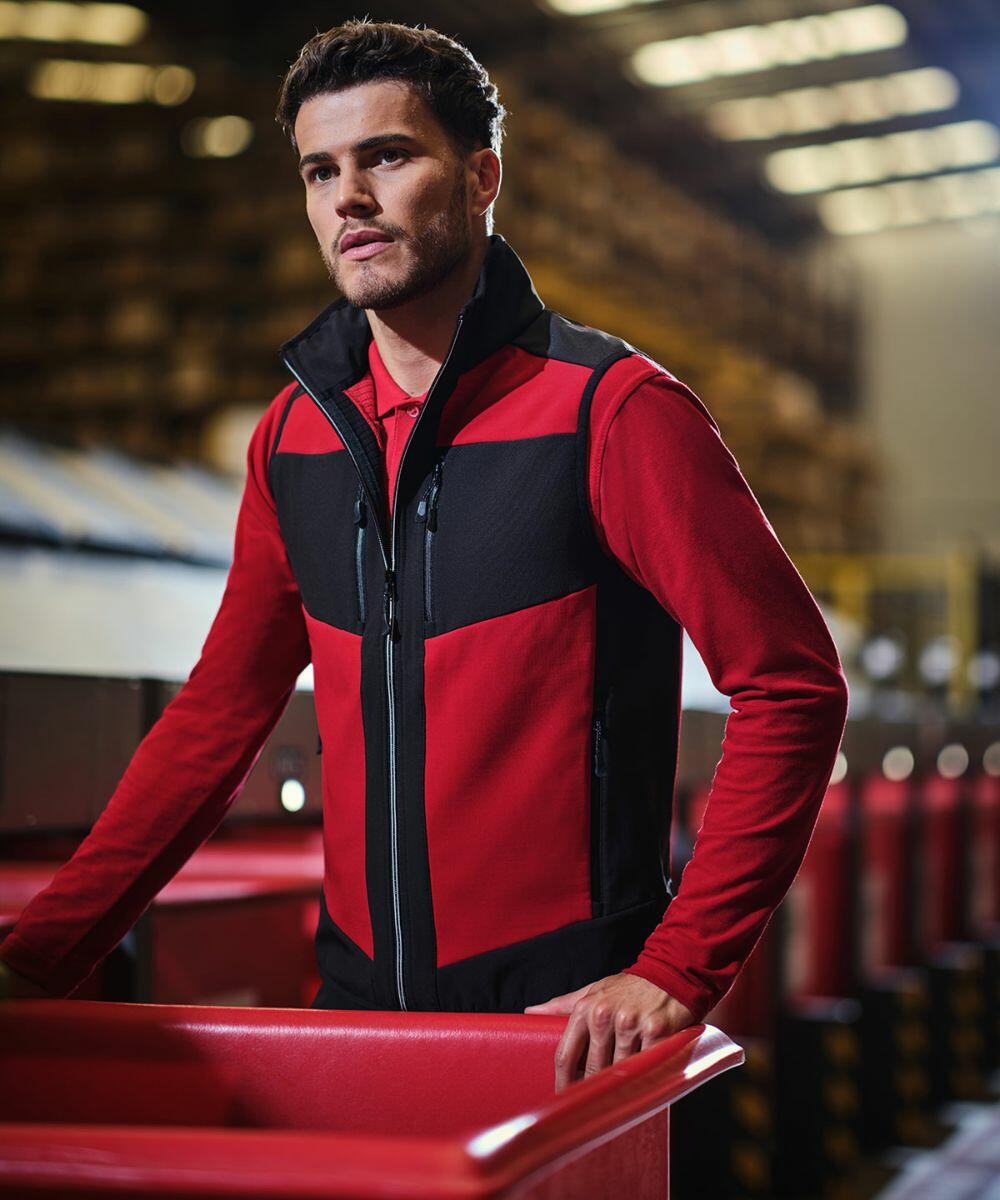Man in a red and black uniform works in a warehouse, standing next to Regatta RG543 containers.