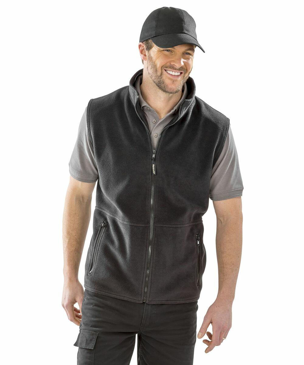 A man wears a black cap, grey vest, and light grey shirt (RE37A by Result), standing and smiling against a white background.