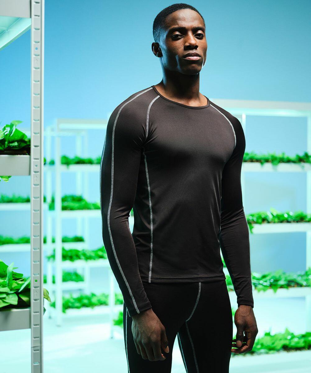 A person in a black Regatta RG621 athletic outfit stands in front of shelves filled with green plants.