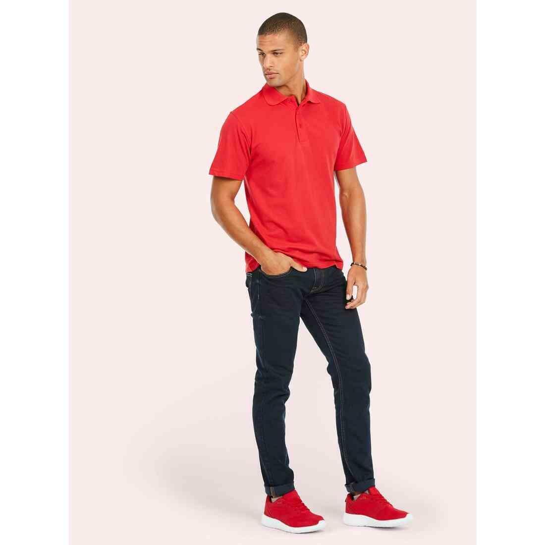 A man wearing a UC124 Red Uneek olympic polo shirt with Blue jeans