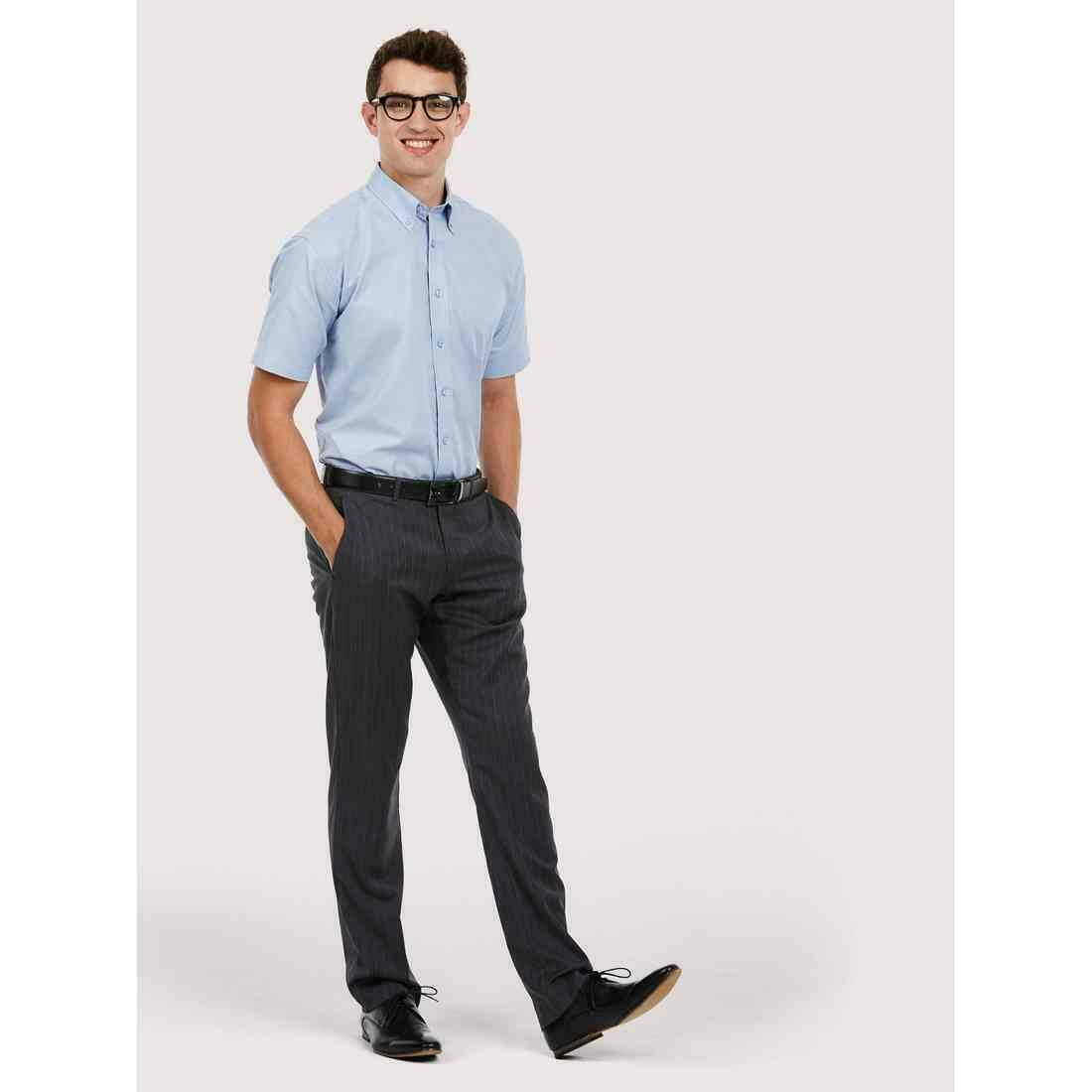 A man wearing a UC702 Light Blue Uneek pinpoint oxford short sleeved shirt with Charcoal trousers