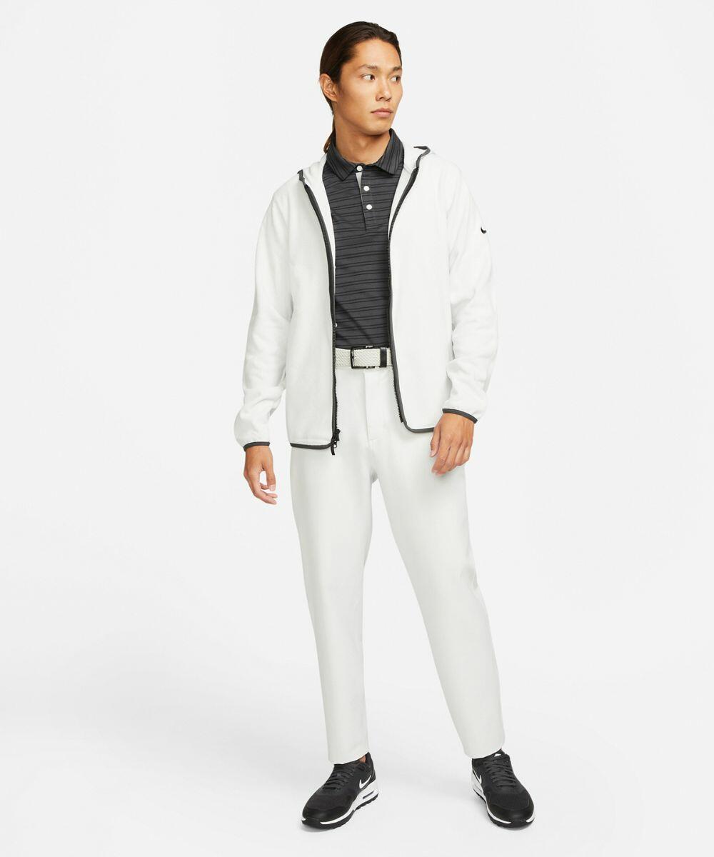 Person wearing a white jacket, black polo shirt, white pants, and Nike NK330 sneakers stands on a plain white background.