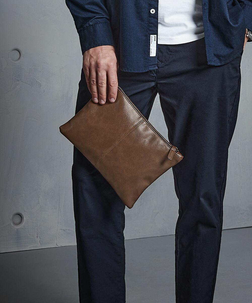 A person in dark pants and a blue shirt holds a Quadra QD889 against a gray background.