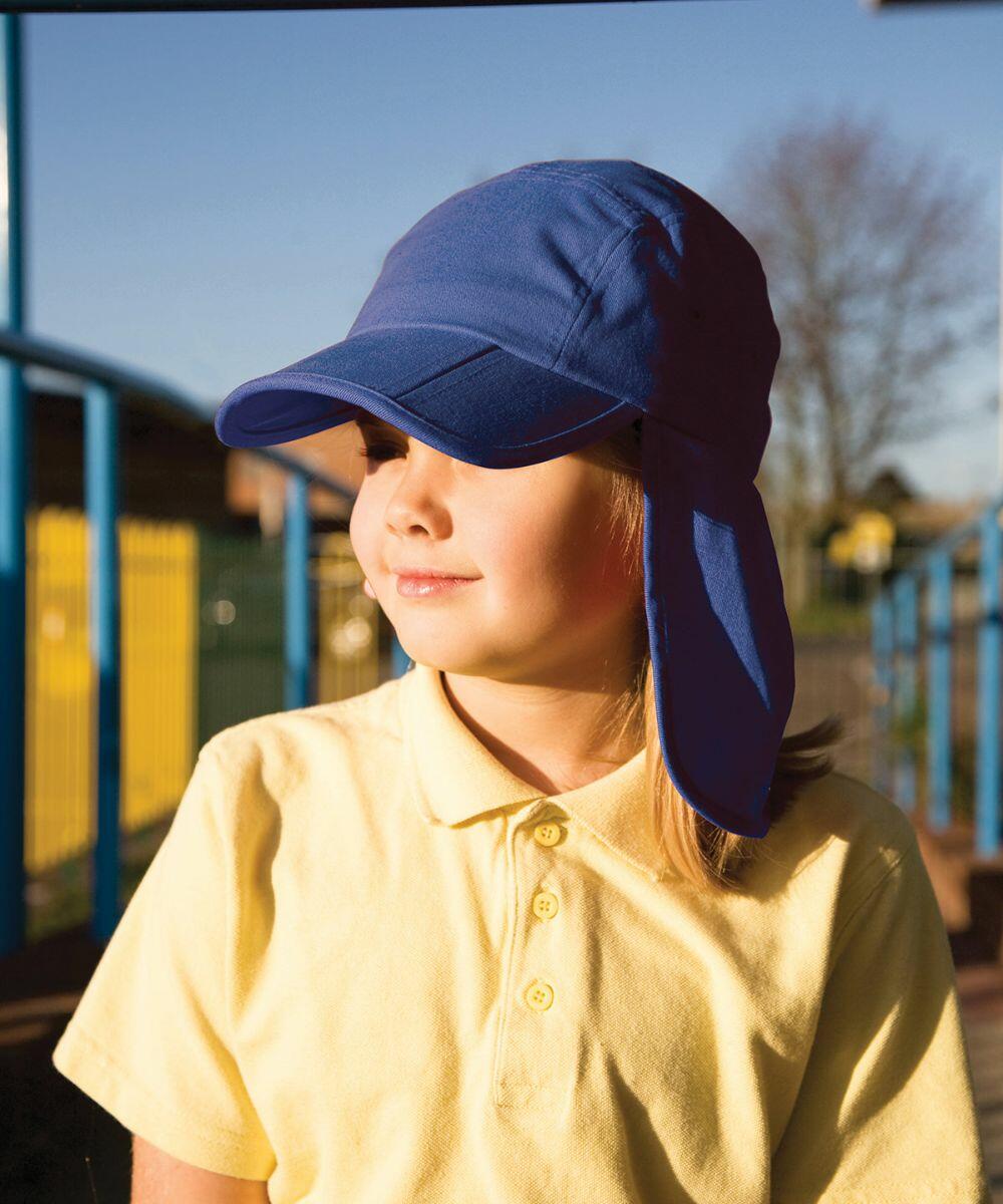 A child wearing a blue sun hat and a yellow RC76J shirt from Result is standing outdoors. The background shows a fence and trees under a clear sky.