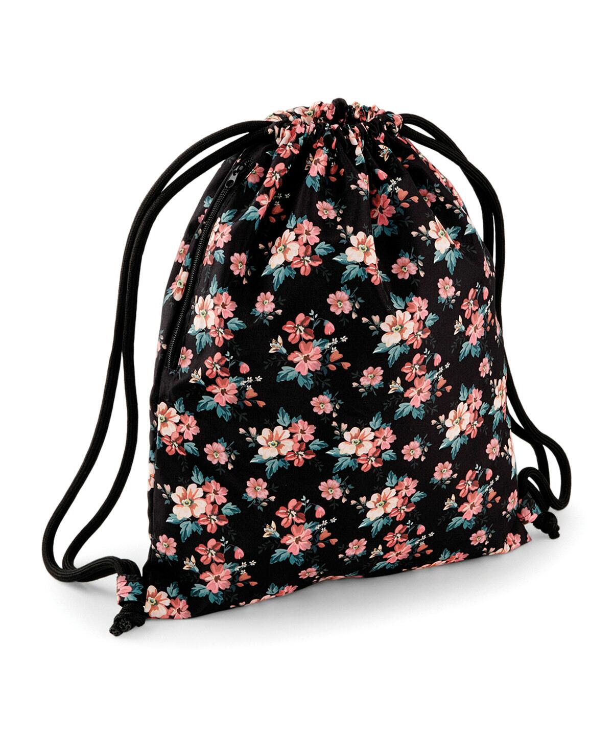 A Bagbase BG180 with a black background, adorned with a vibrant floral pattern featuring red, pink, and white flowers. The bag has black drawstrings for closure and wearing as shoulder straps.