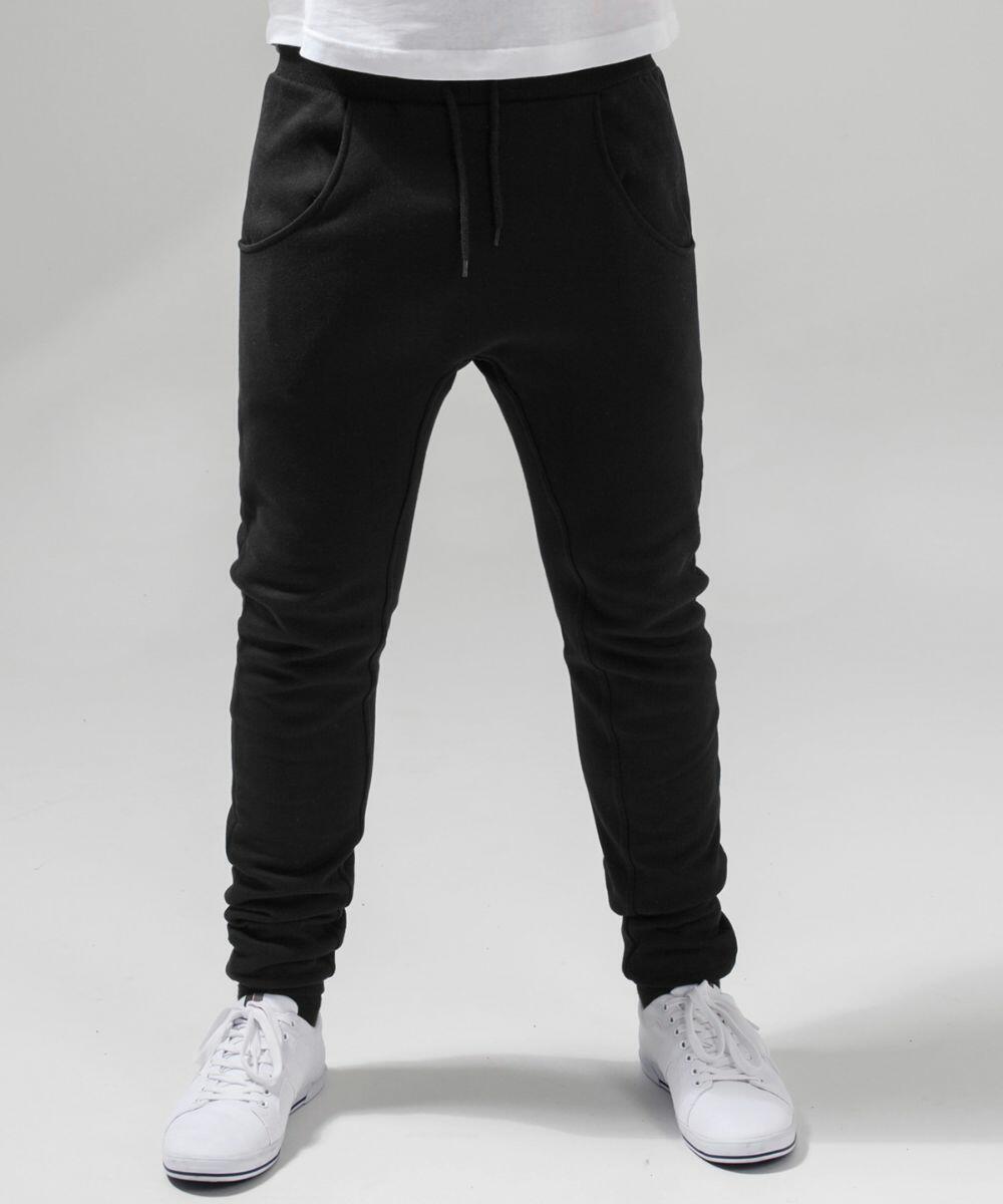 Person wearing Build Your Brand's BY013 jogger pants with an elastic waistband and drawstrings, paired with white sneakers. The background is plain white. The person's hands are in the pockets of the joggers, and the photo is cropped below the waist.