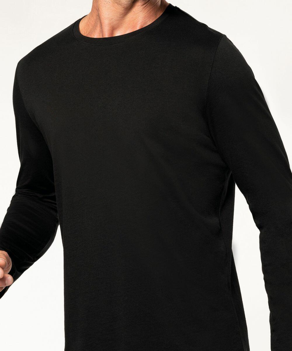A person wearing a Kariban KB359 black long-sleeve shirt is captured from the neck to the waist, standing against a plain background.