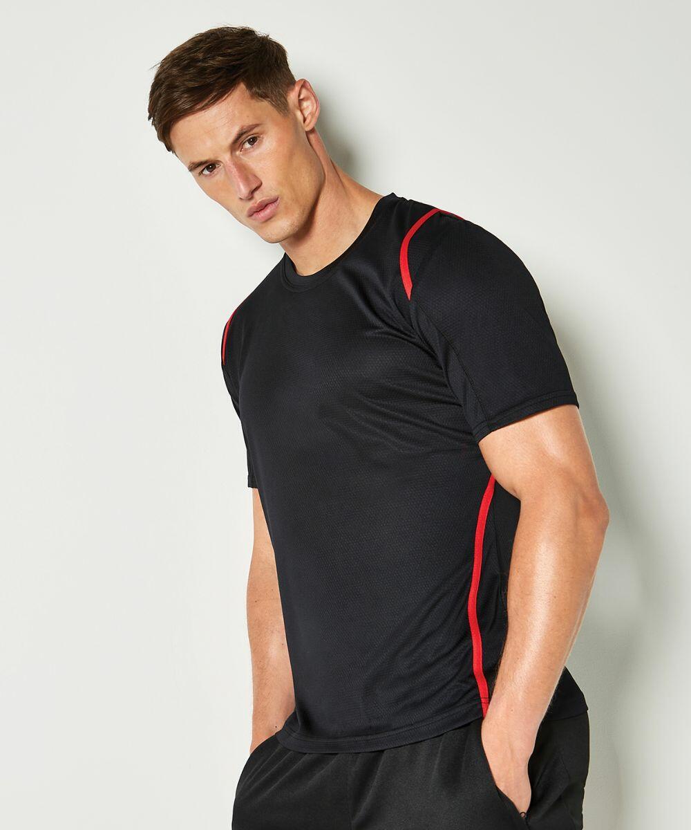A man in a black KK991 athletic shirt with red trim by Kustom Kit stands against a white background with his hands in his pockets.