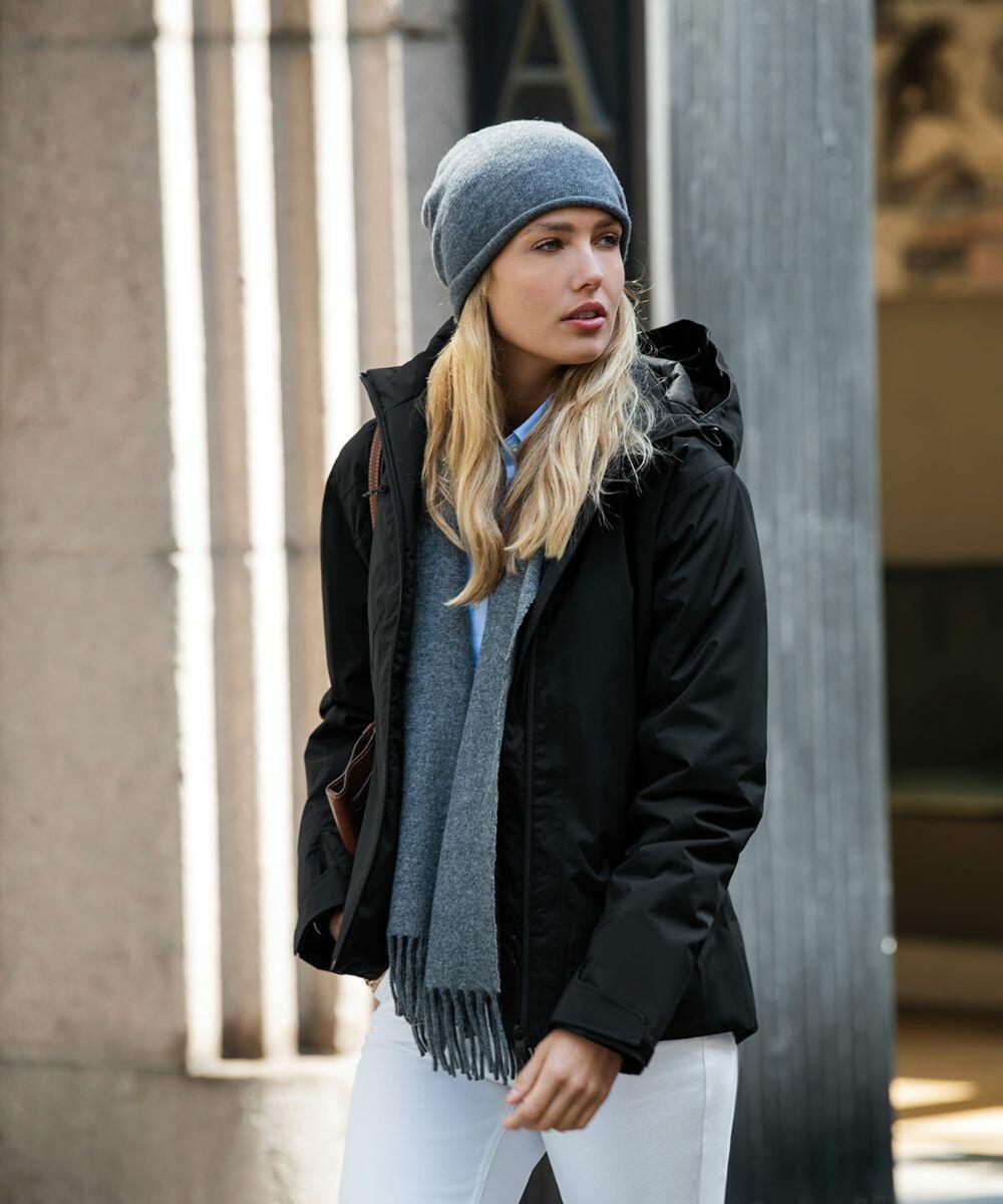 A woman wearing a black Nimbus NB88F jacket, gray scarf, and gray beanie stands in front of a building.