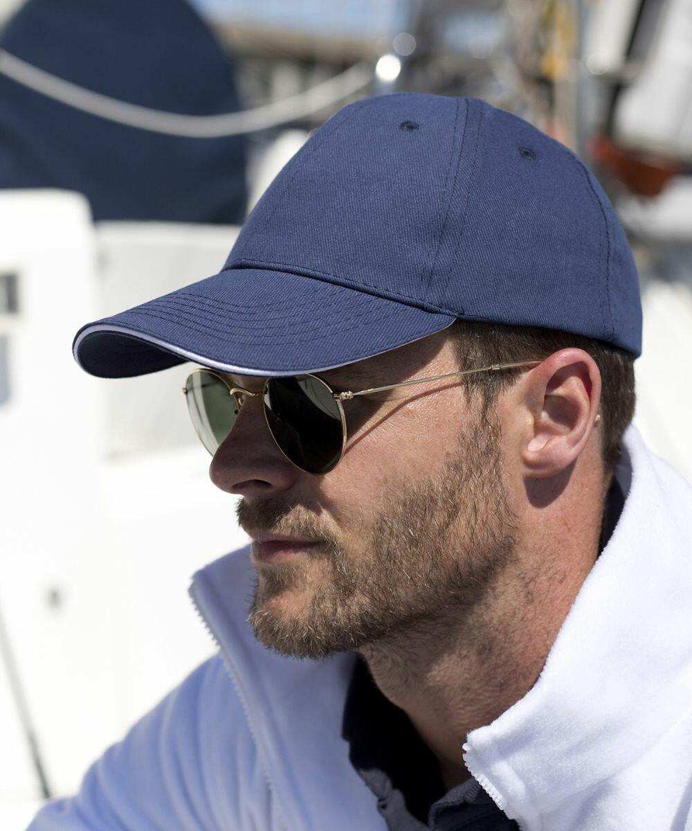 A person wearing a blue cap, sunglasses, and a white Result RC91X jacket is looking ahead.