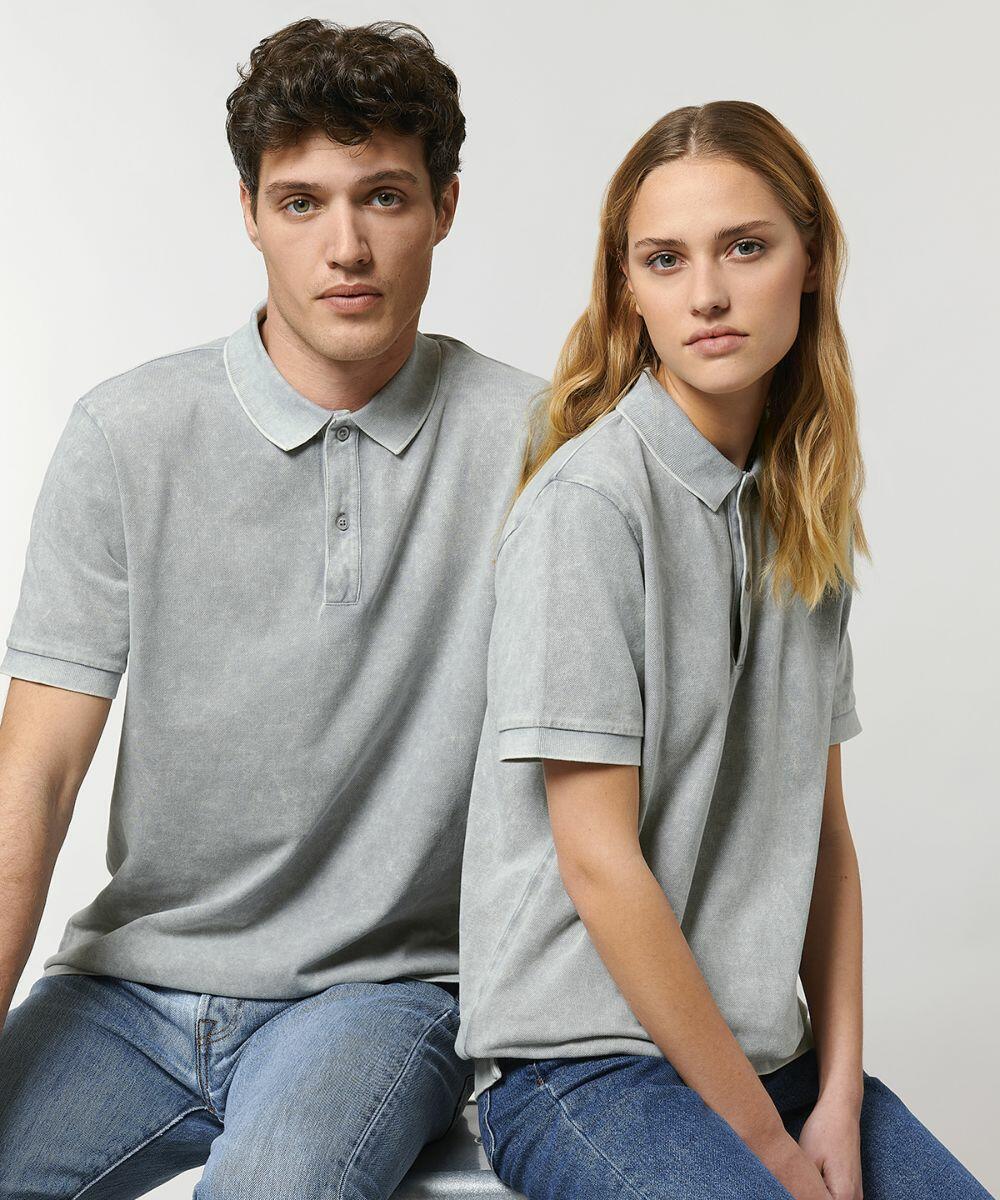 Two people sit side by side, both wearing light gray Stanley/Stella SX129 polo shirts and blue jeans, against a plain background.