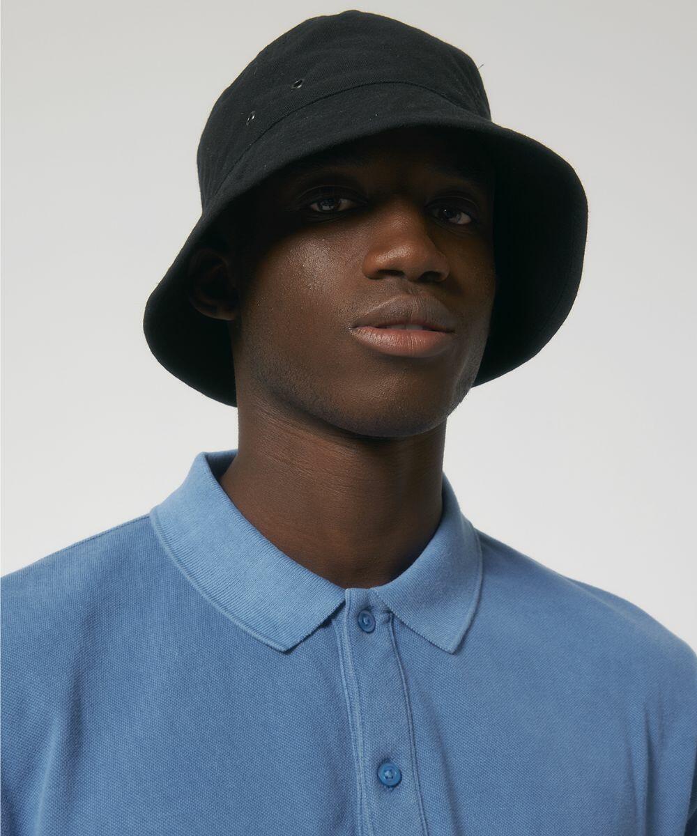 A person wearing a black bucket hat and a blue collared Stanley/Stella SX163 looks forward against a neutral background.