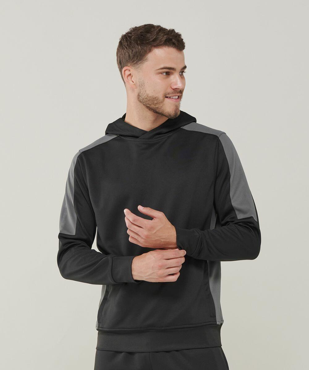 A man with short hair is wearing a black and gray Finden & Hales LV341 hoodie and looking to the side. He is holding his left wrist with his right hand.