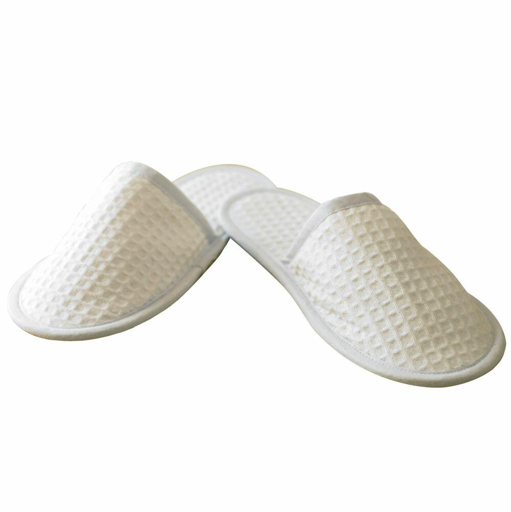 The TC066 by Towel City is a pair of white, waffle-texture slippers featuring closed toes, displayed against a white background.