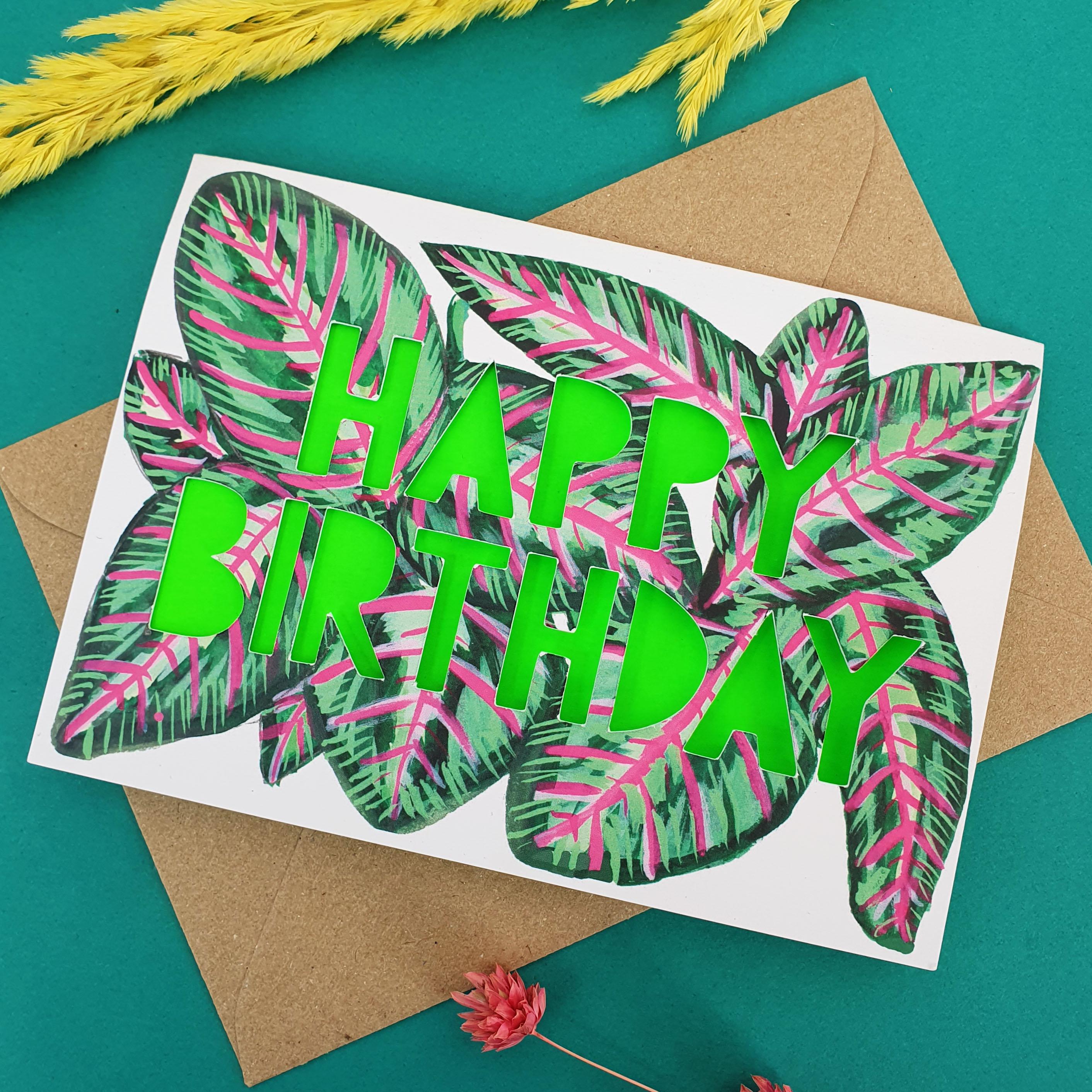 close of of Paper cut card with 'Happy Birthday' typography on a printed stripy pink and green leaf 350 gsm card with neon green liner.