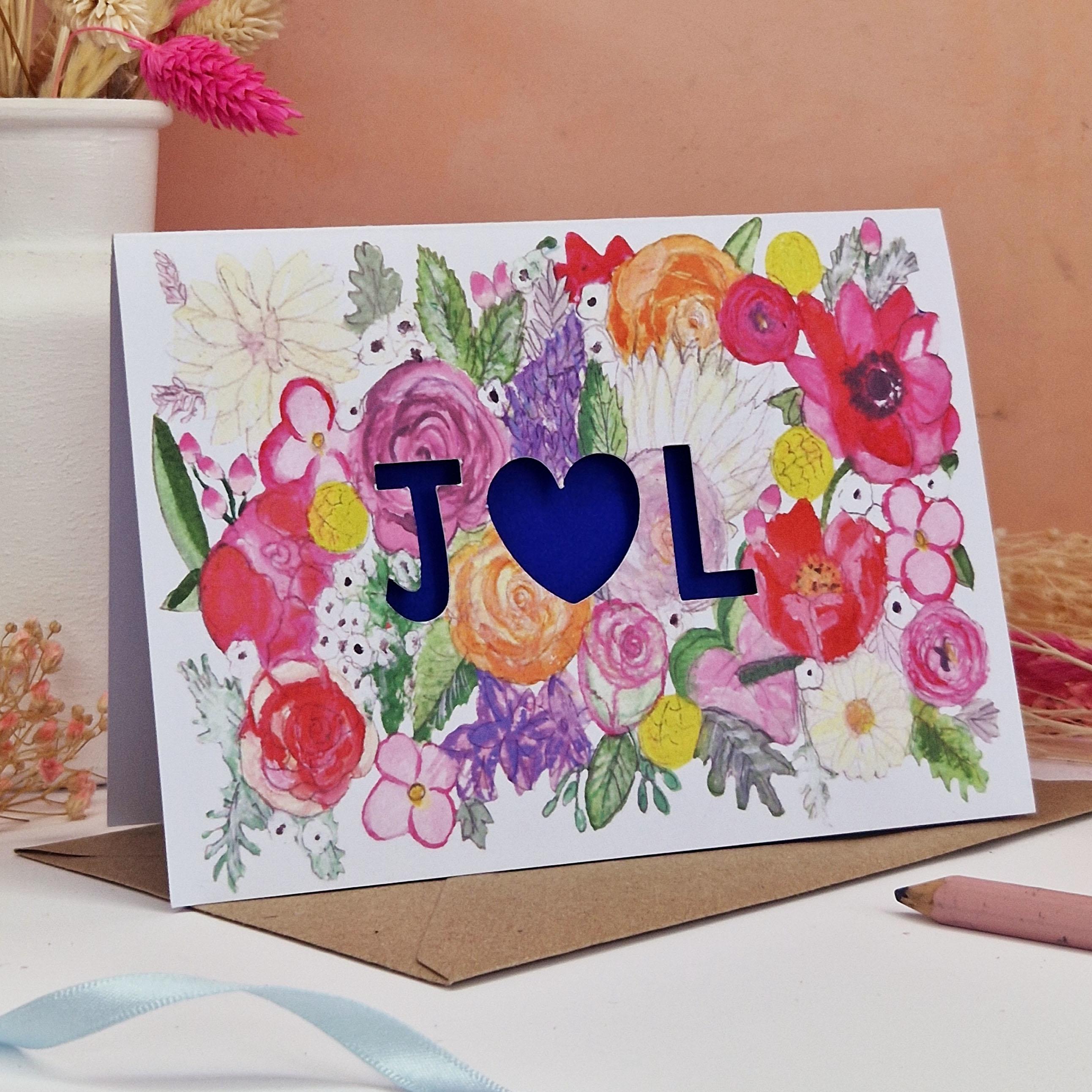 Floral Card with Paper cut text that is personalised with Initials with bright floral background and blue paper liner inside.
