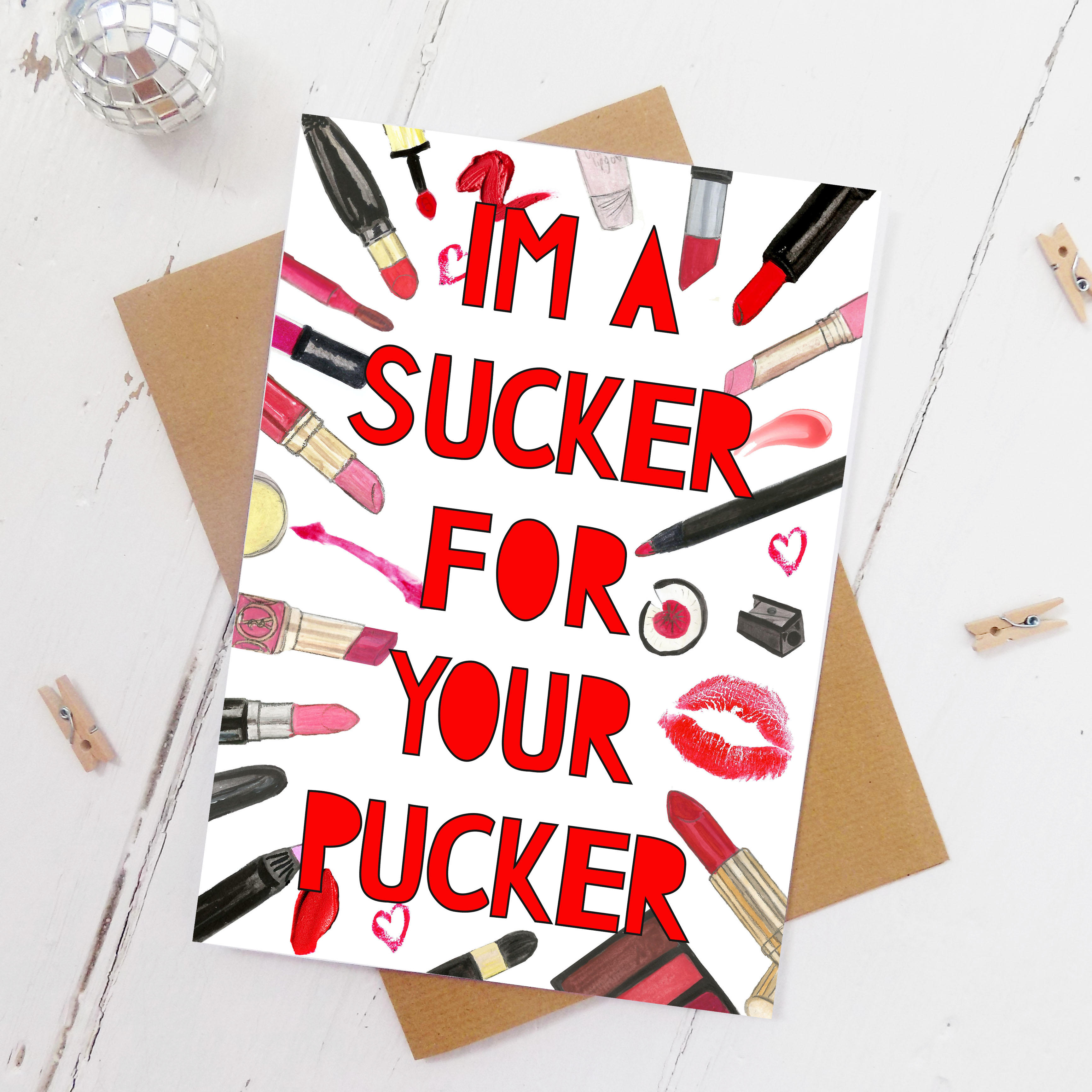 Watercolour illustrations of various lipsticks, lip penciis and lipstick kisses with paper cut typography cut out from top to bottom saying 'I''m a sucker for your pucker'