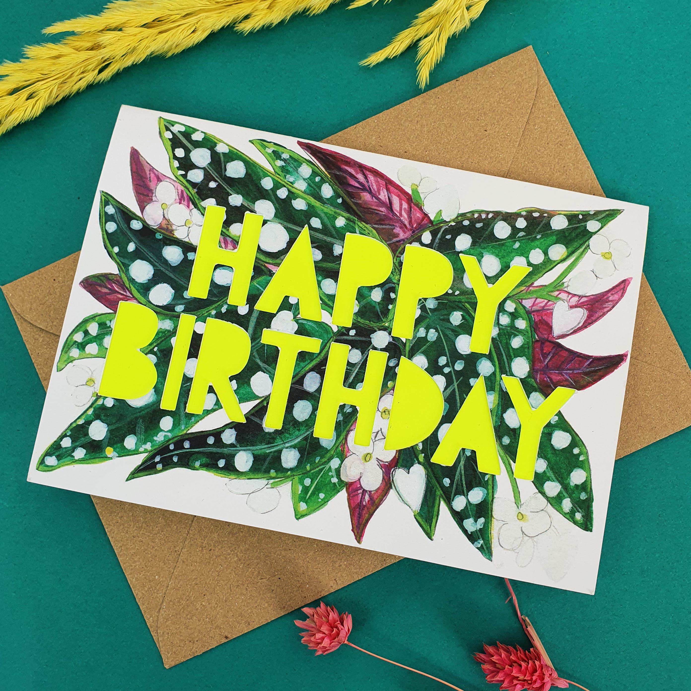 Close up of paper cut card with 'Happy Birthday' typography on a printed spotty begonia 350 gsm card with neon yellow liner.