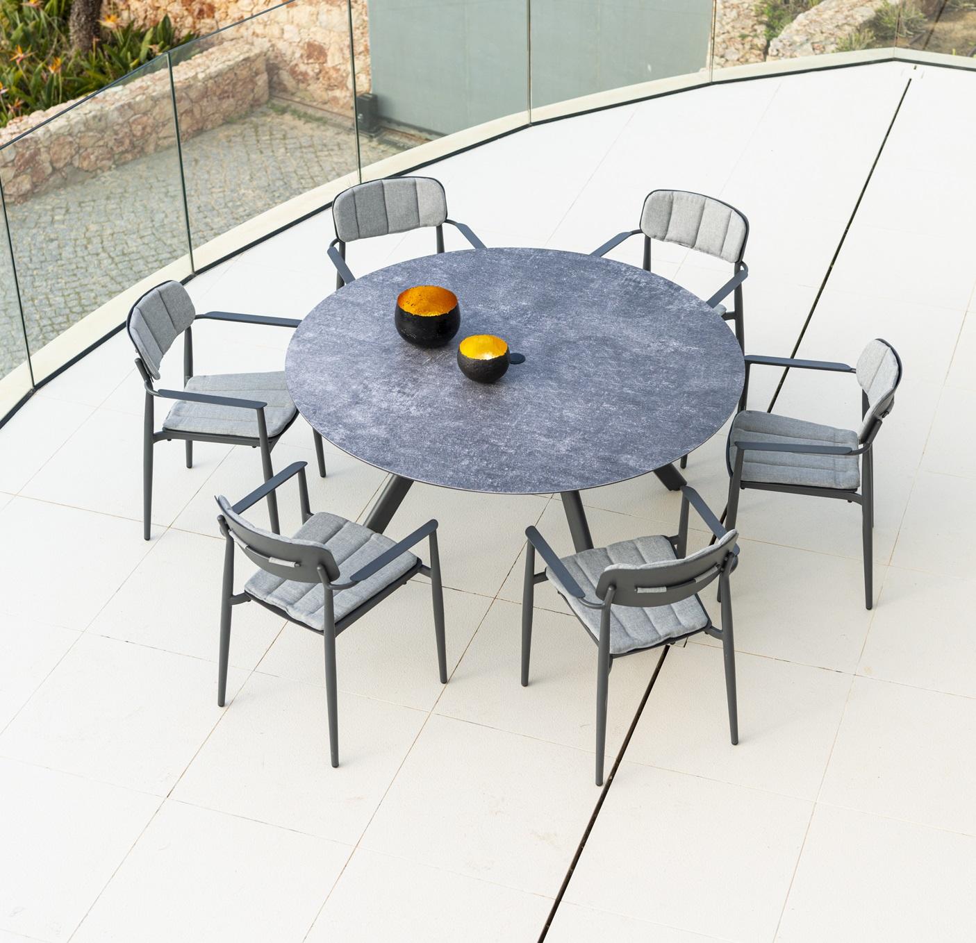 round modern garden dining table in grey aluminium metal with 6 garden dining arm chairs and weatherproof cushions
