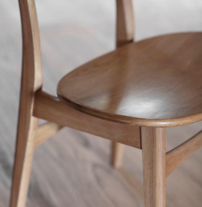 detail of curved oak seat on spindle back and leg indoor dining chairs