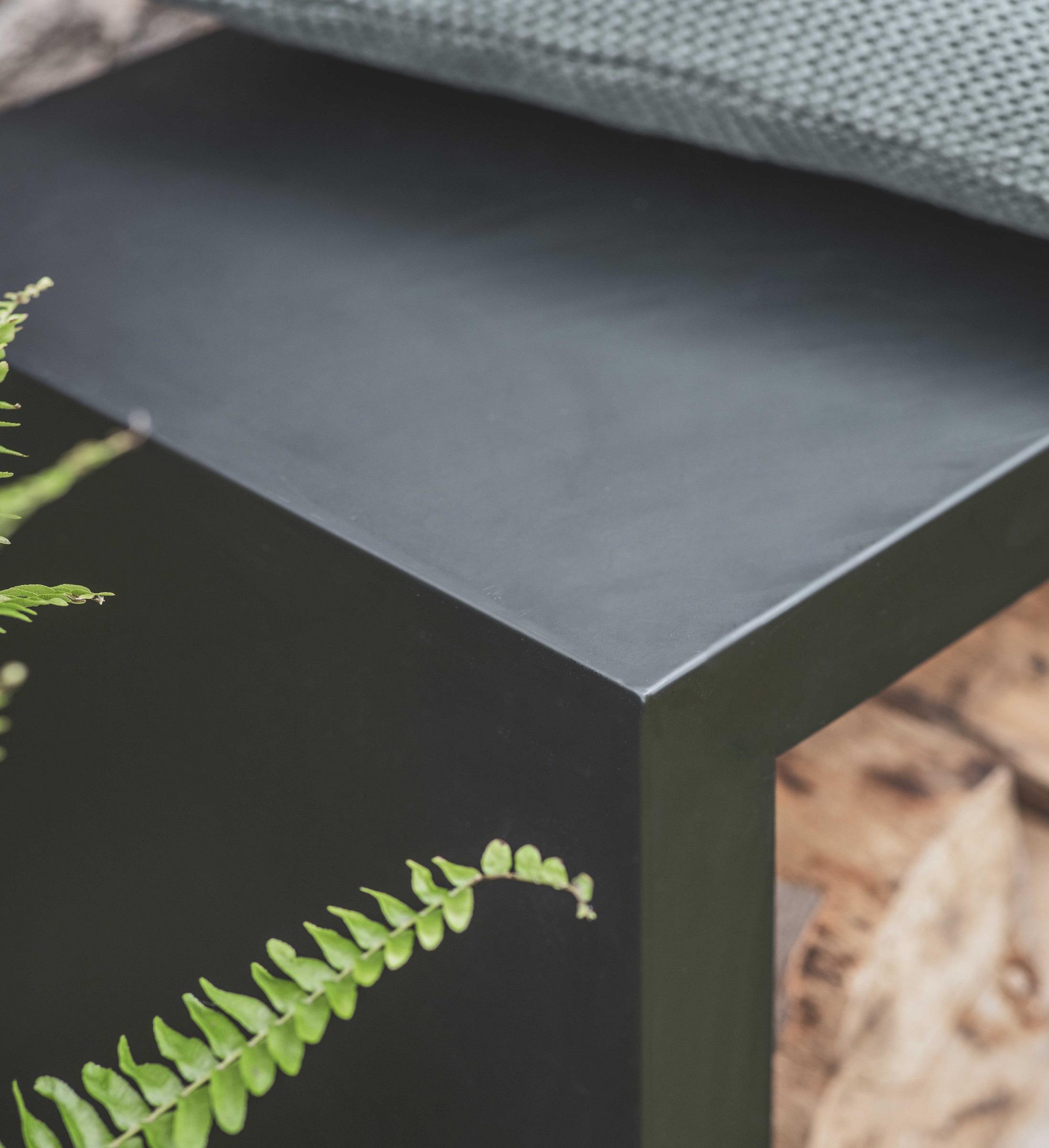 close up of black metal modern garden log store and outdoor bench seating