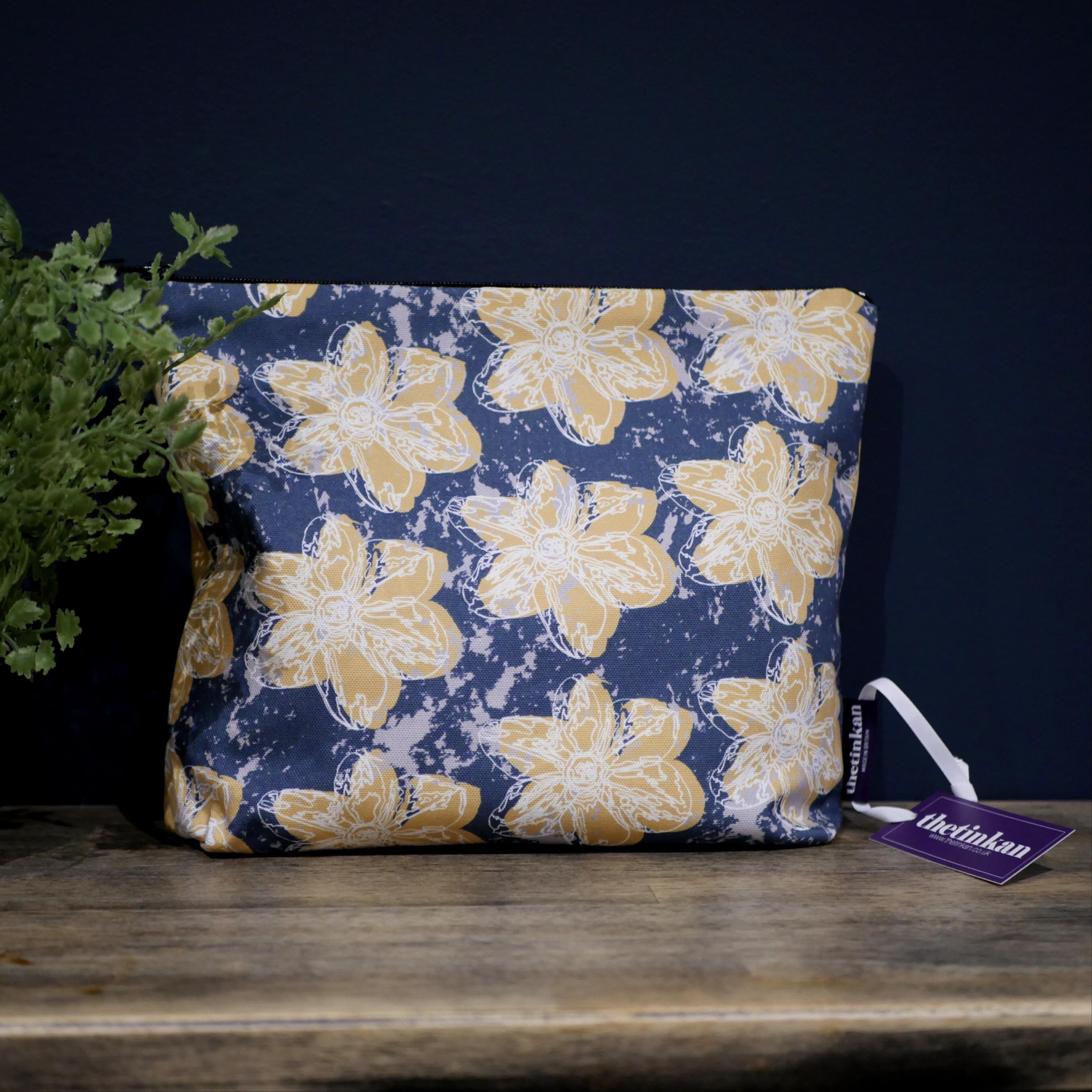 Mustard yellow flower with a matching coloured reverse, set on an oxford blue background with a light grey colour splash. Designed by thetinkan, the flower splash travel beauty washbag featuring the white traced outline of a?narcissus flower is made from panama cotton with black waterproof lining and matching black sturdy zip. Generously sized for all your travel or home needs.? VIEW PRODUCT >>