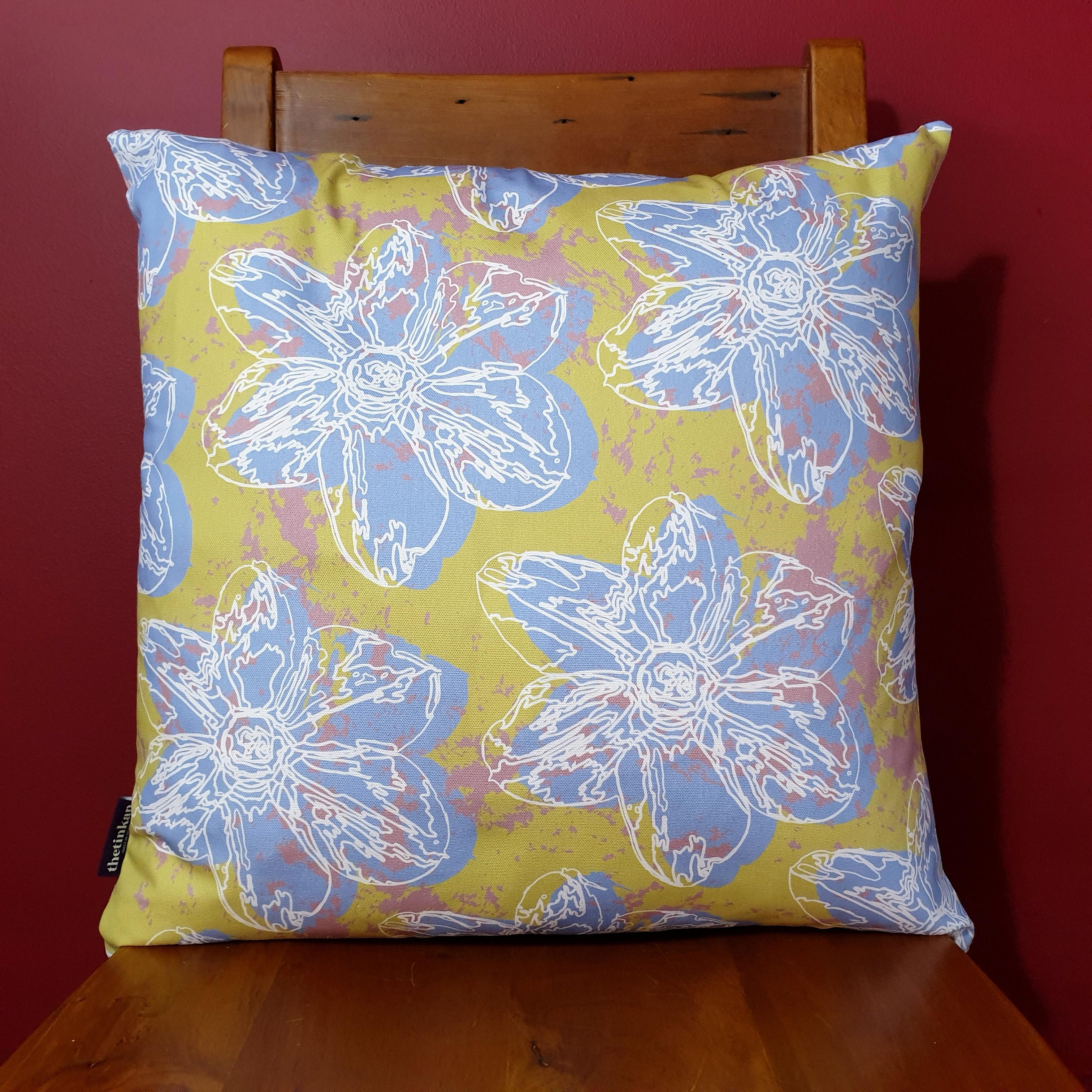 Double-sided 51cm square Flower Splash cushion designed by thetinkan. Pale blue narcissus flower with white traced outline set within a light olive green background with salmon pink paint splashes. Available with an optional luxury cushion inner pad. VIEW PRODUCT >>