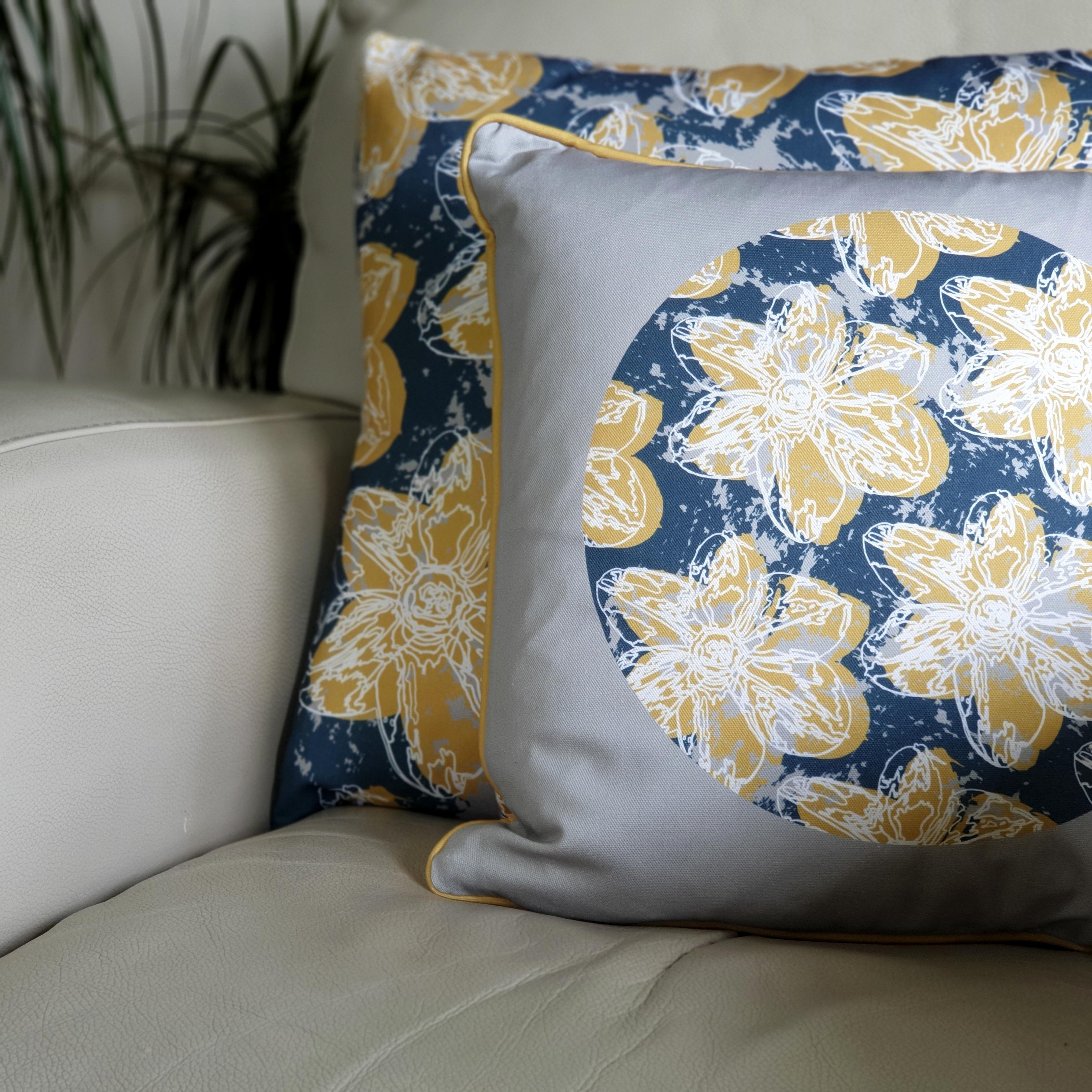 Double-sided 45cm square & 51cm square Flower Splash cushions, showing both sides, designed by thetinkan. Mustard yellow narcissus flower with white traced outline set in an oxford blue coloured circle with pale grey paint splashes and pale grey surround. Available with an optional luxury cushion inner pad. VIEW PRODUCT >>